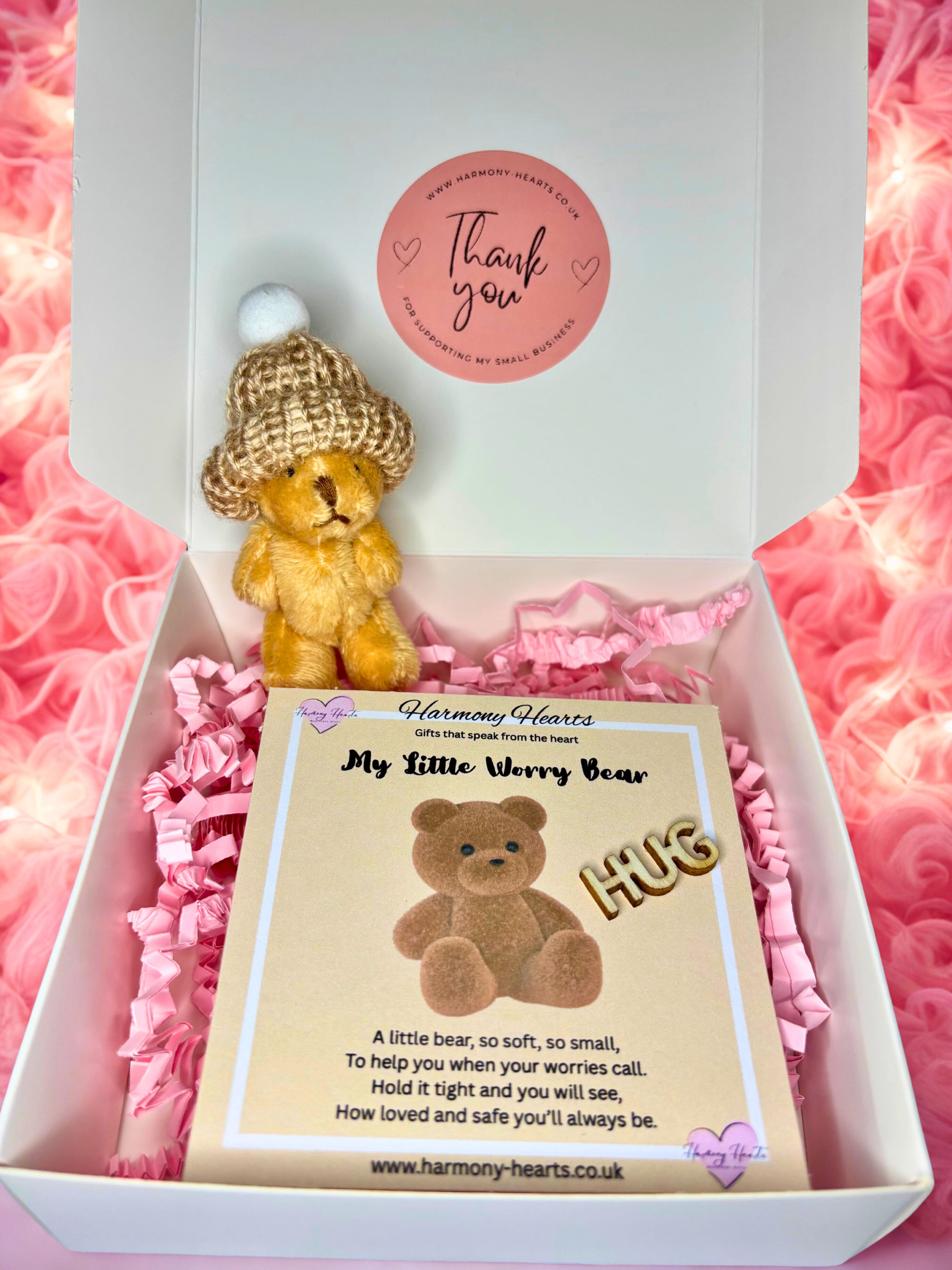 Small teddy bear with a gold hat in a box with pink tissue paper, featuring a 'thank you' card.