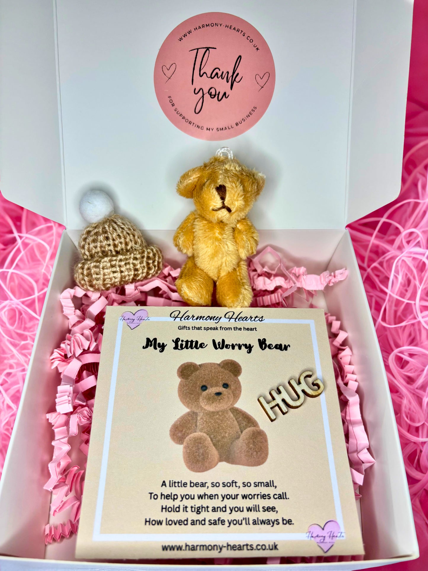 Small teddy bear in a gift box with a card and decorative elements.