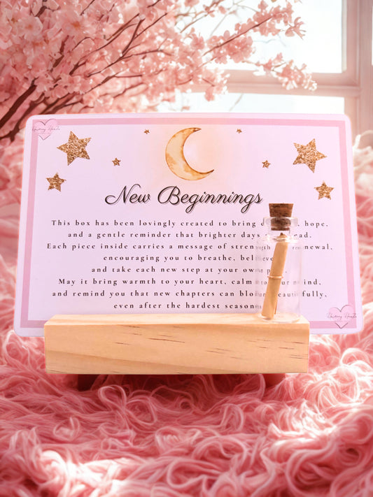 Decorative item with a card and small wish bottle on a pink surface with cherry blossoms in the background