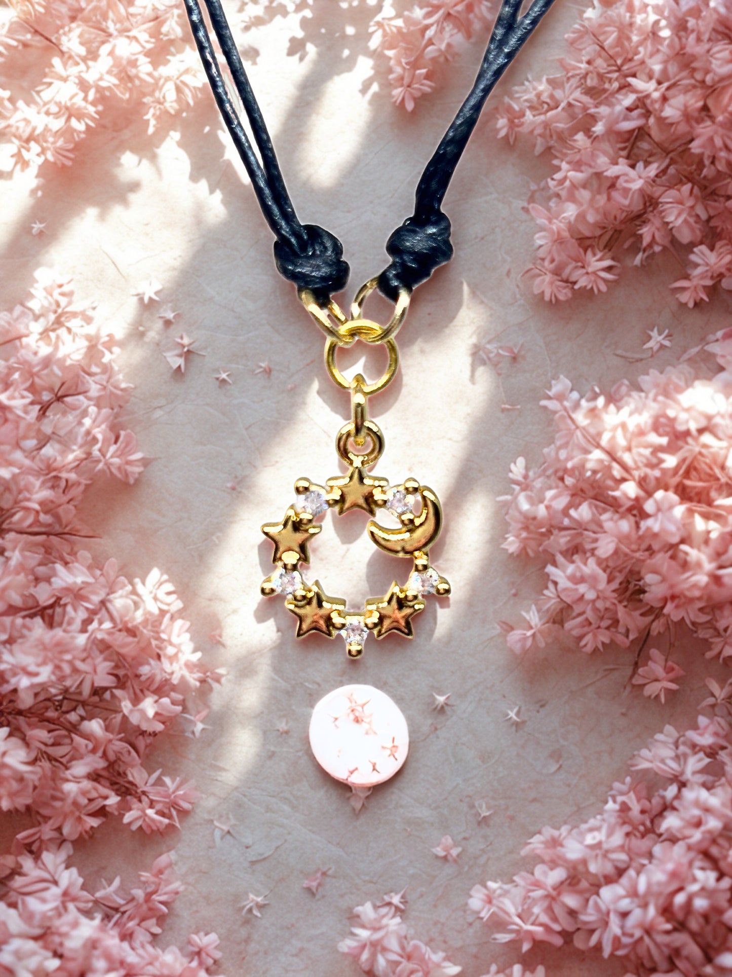 Braceelt with a gold moon charm on a pink floral background