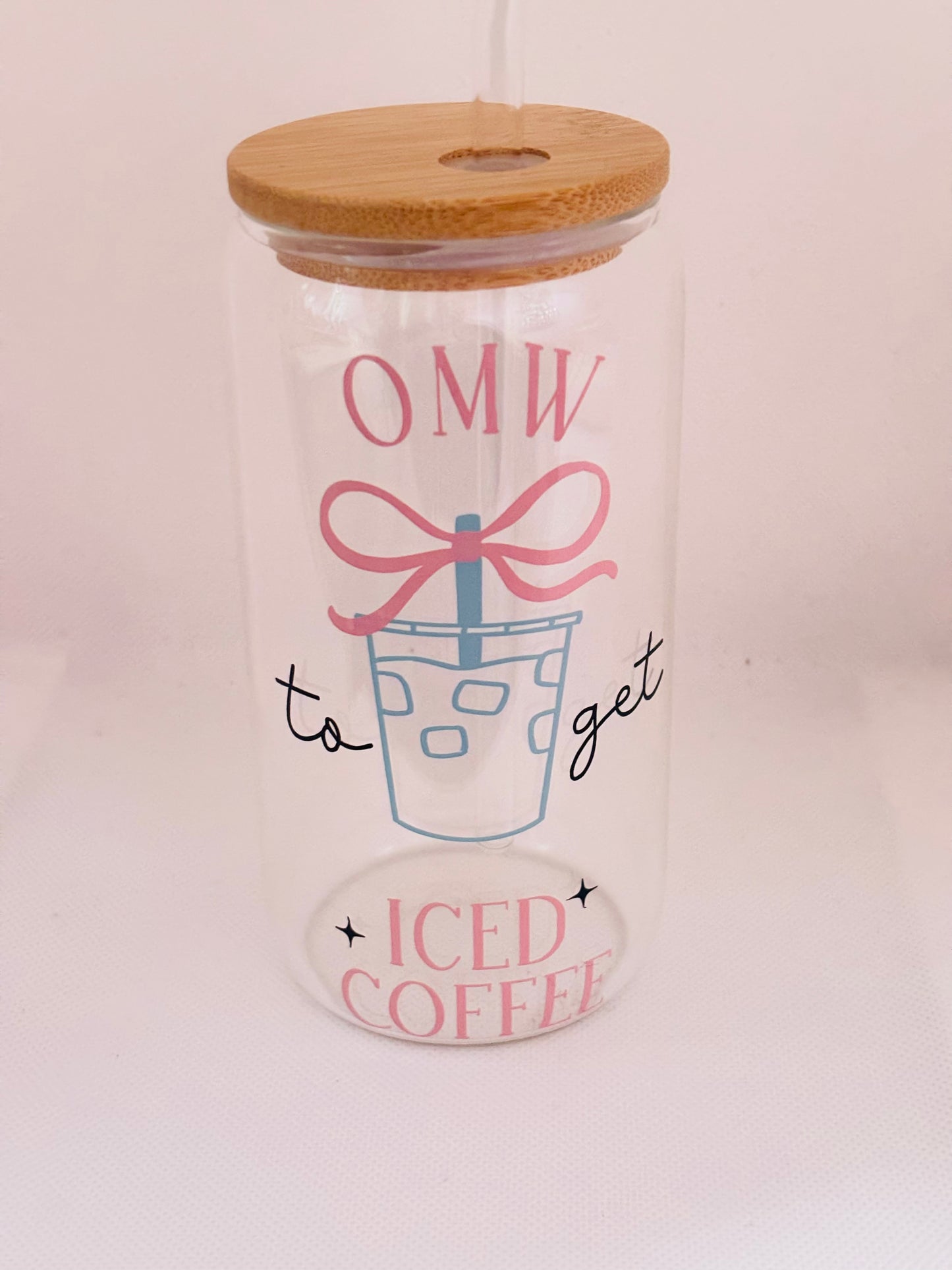 Glass tumbler with wooden lid featuring text and a graphic of iced coffee.