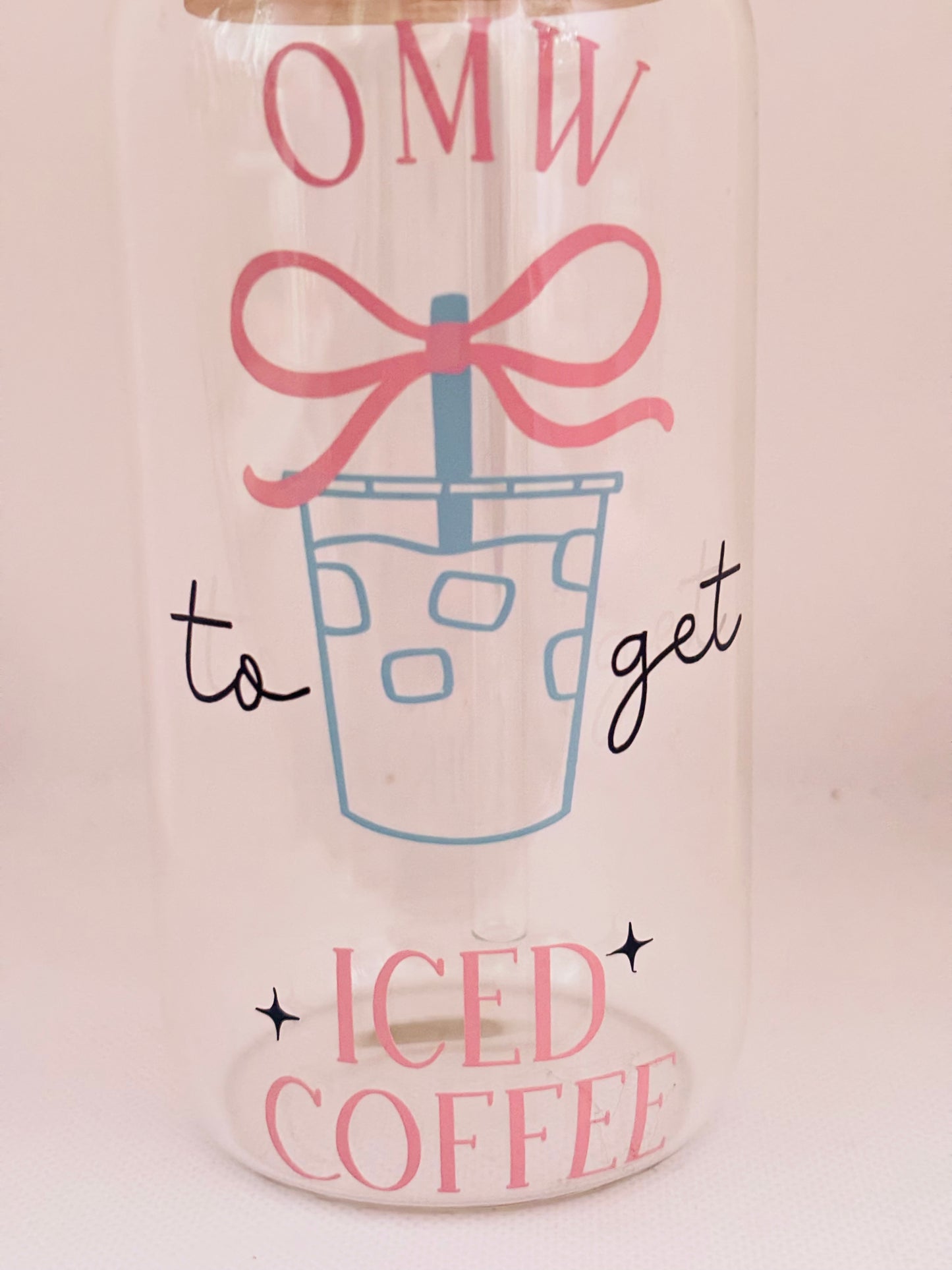Glass cup with a design of iced coffee, a pink bow, and text on a light background