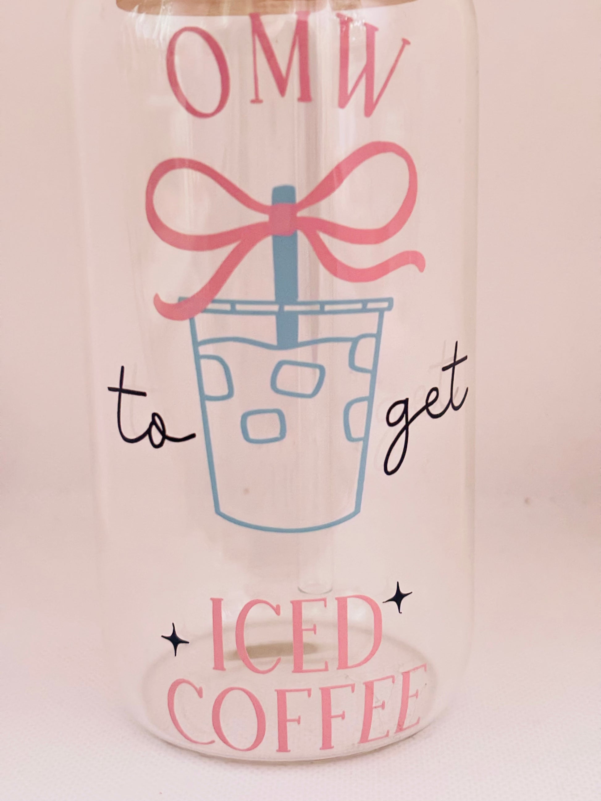 Glass cup with a design of iced coffee, a pink bow, and text on a light background