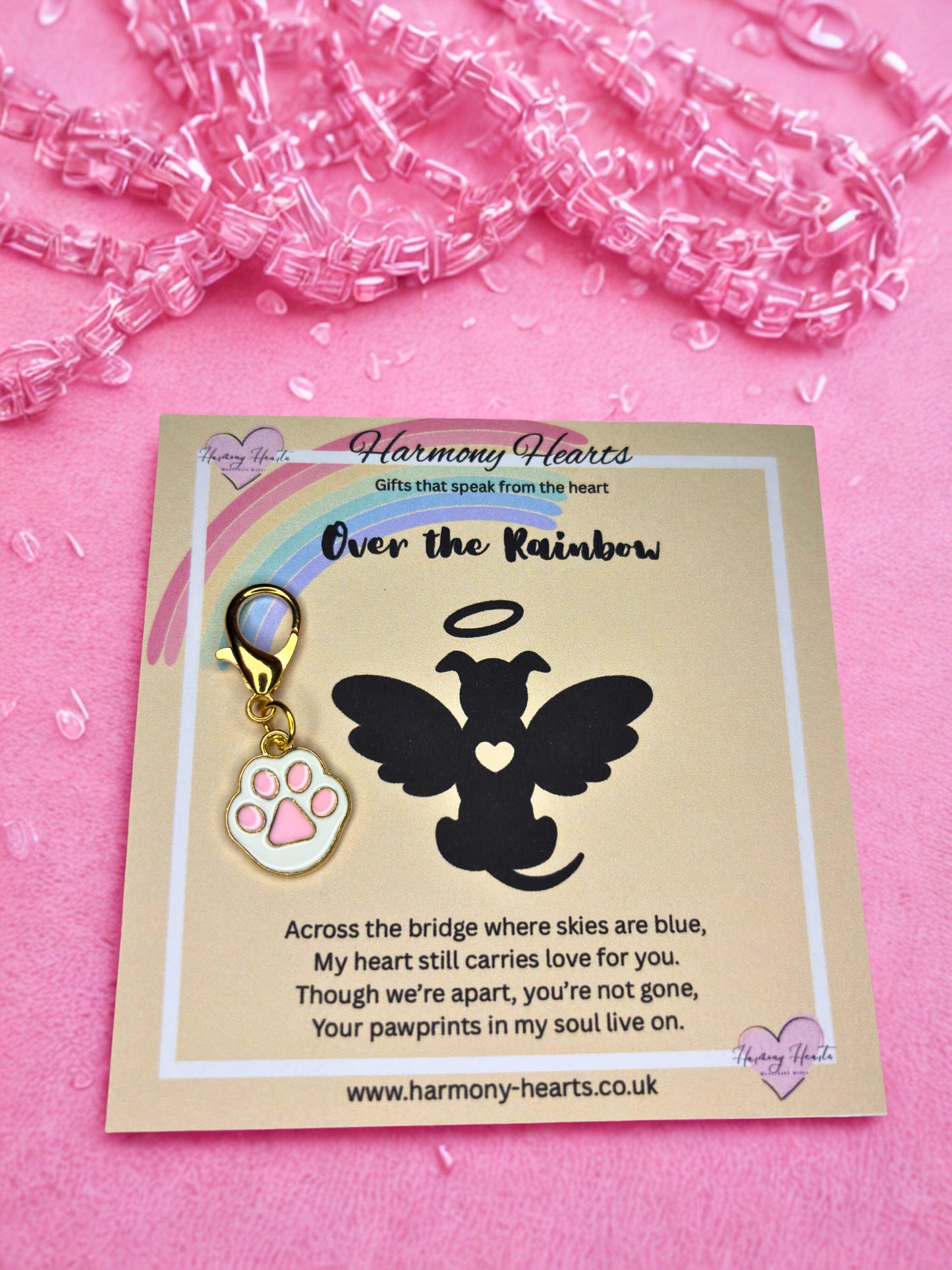 Dog tag with angel wings and paw print on a card with text, against a pink background.