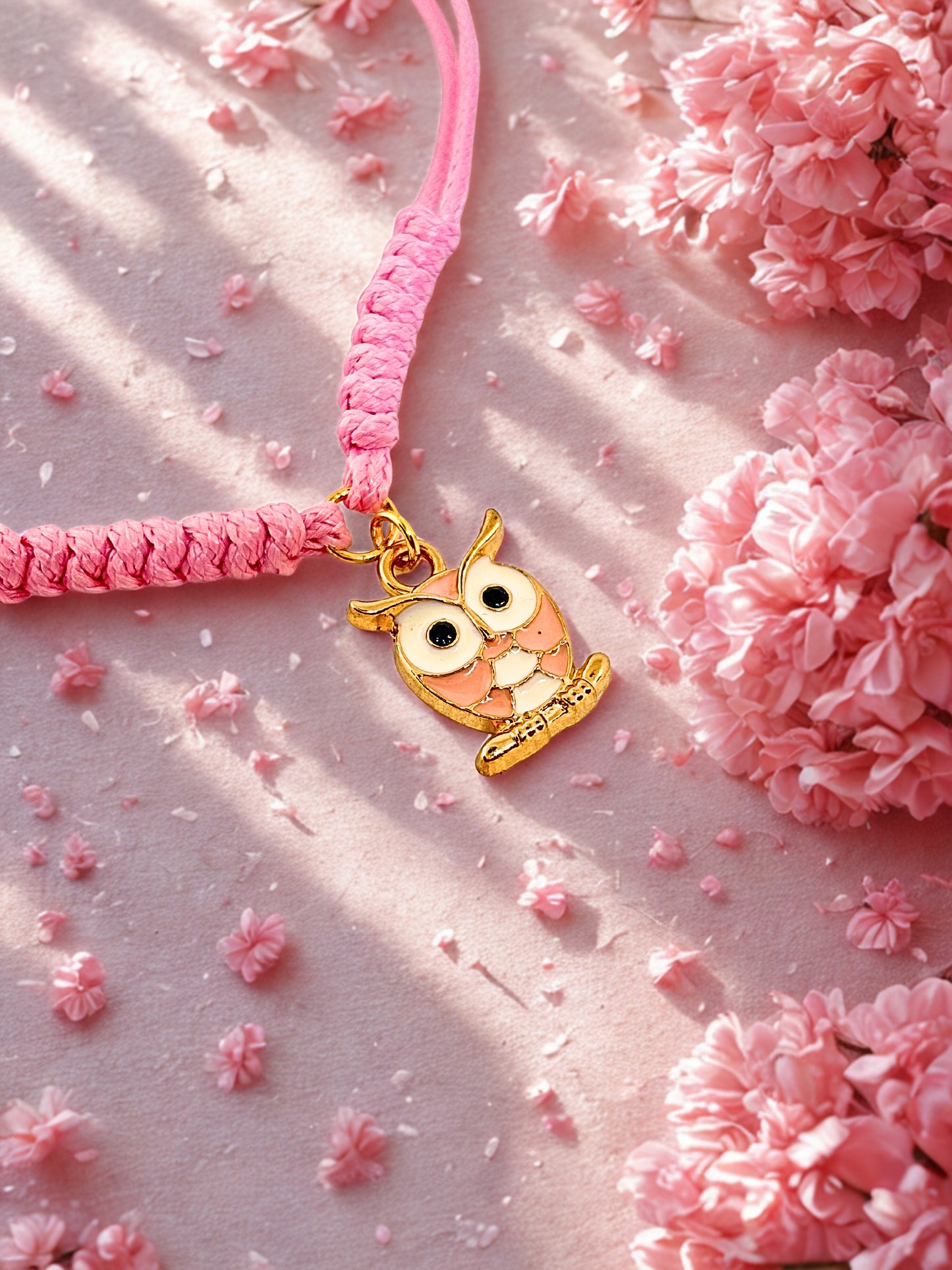 Pink cord bracelet with a owl charm on a pink background