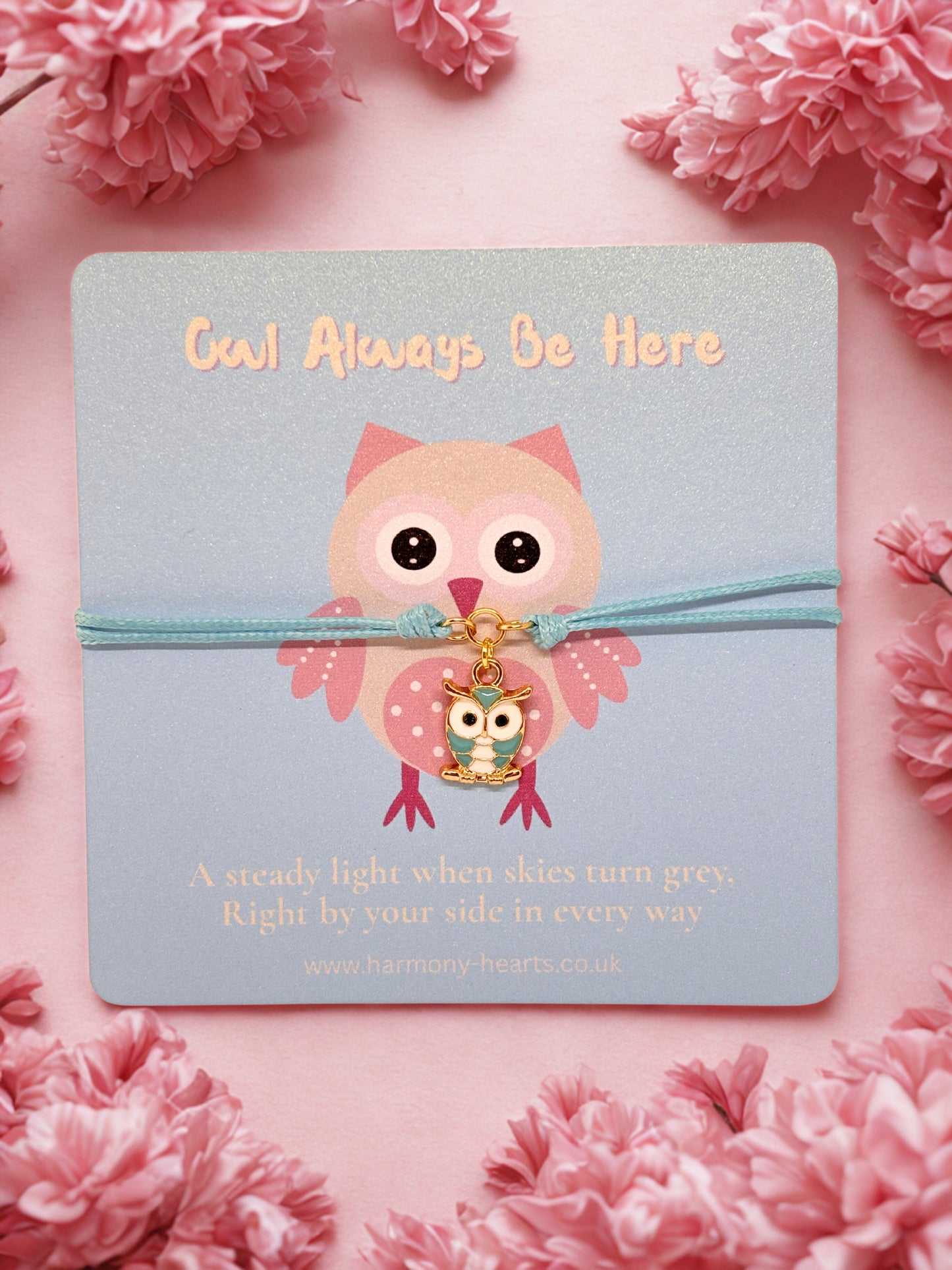 Owl charm bracelet on a branded Harmony Hearts card with 'Owl Always Be Here' text, surrounded by pink flowers.