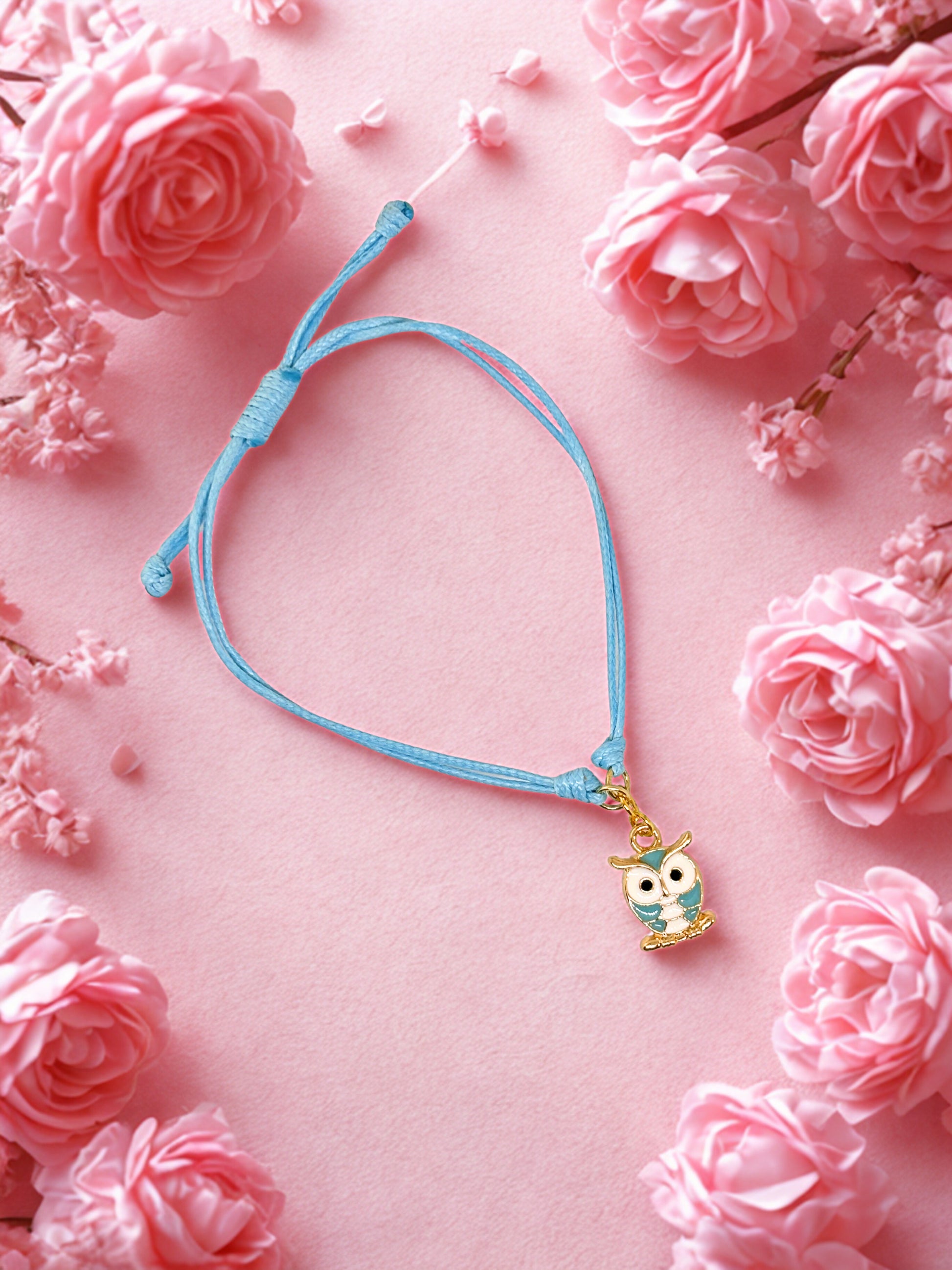 Blue bracelet with an owl charm on a pink floral background
