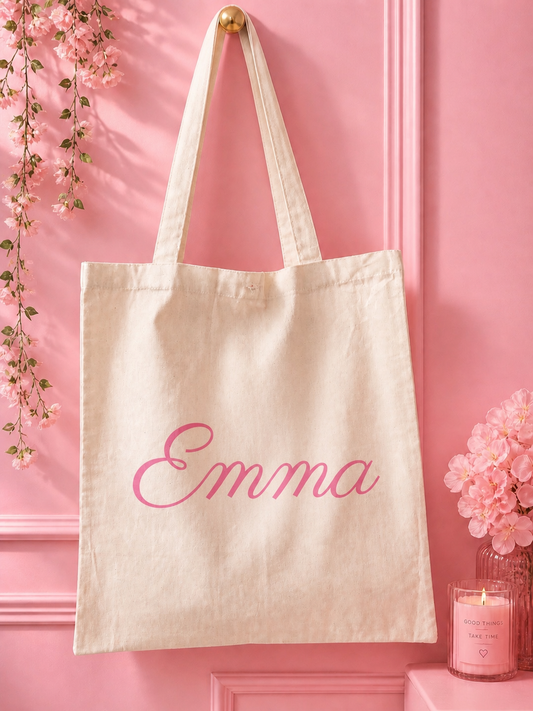 Beige tote bag with 'Emma' in pink text on a pink background with decorative elements.