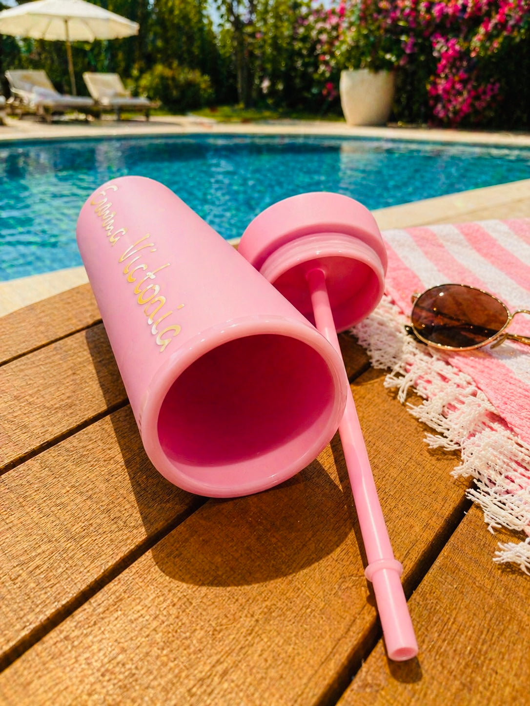 Pink personalised tumbler on a deck by a pool