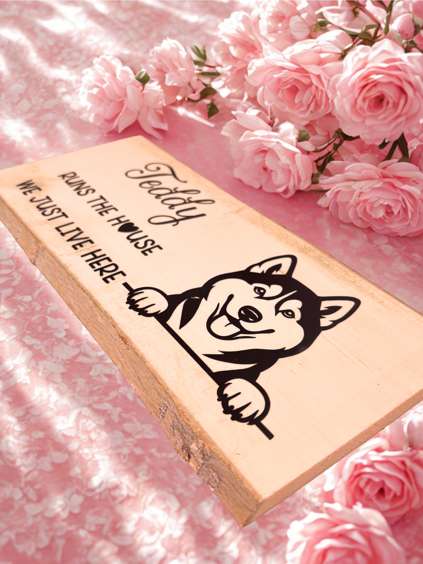 Wooden sign with a dog illustration and text on a pink floral background