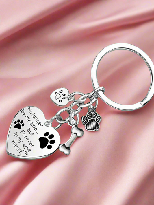 Keychain with heart-shaped pendant, paw prints, and bone charm on a pink fabric background
