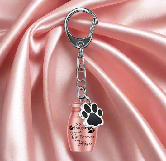 Keychain with paw print and pink urn on pink satin background