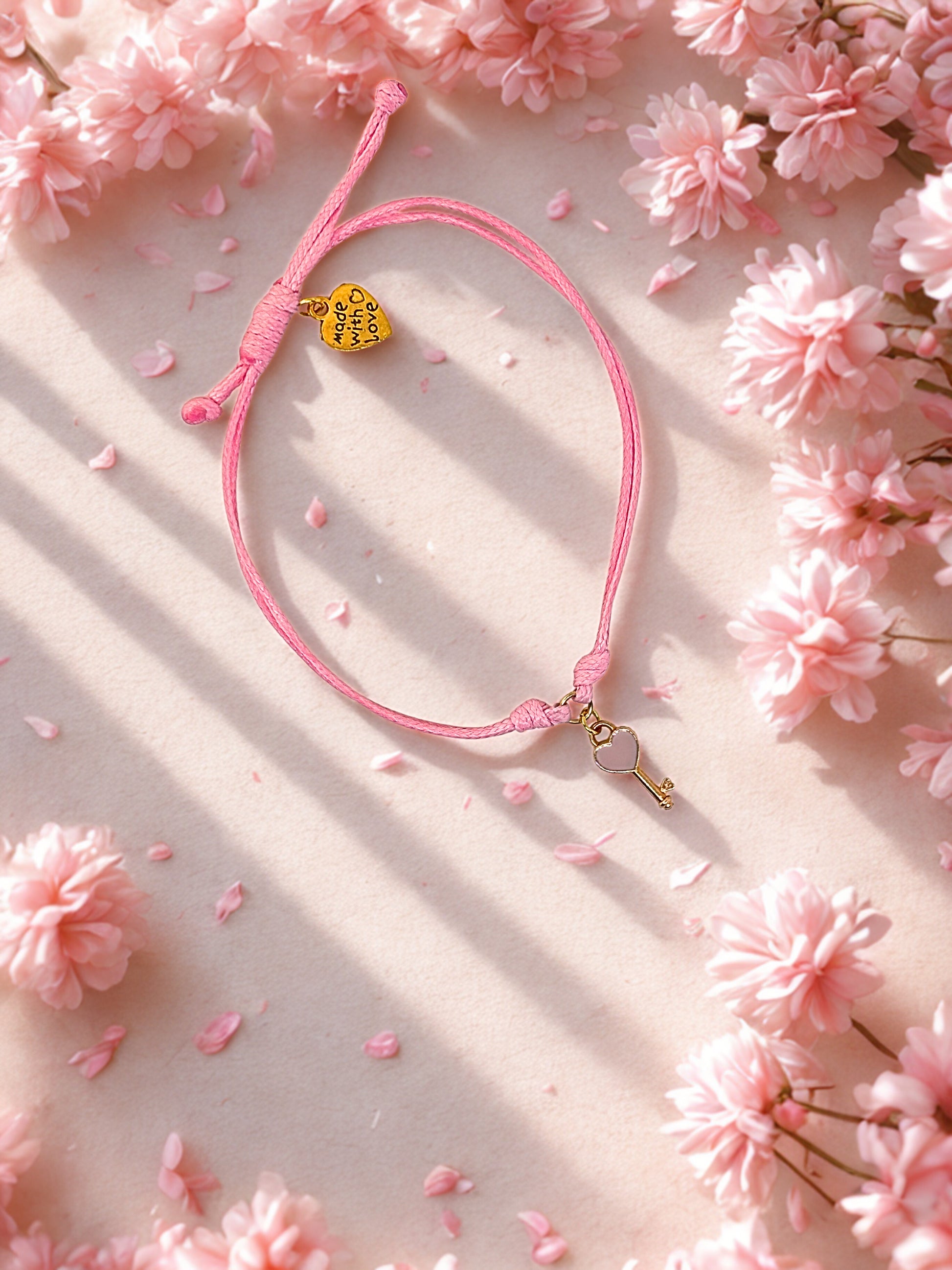 Pink bracelet with gold key charm on a pink floral background