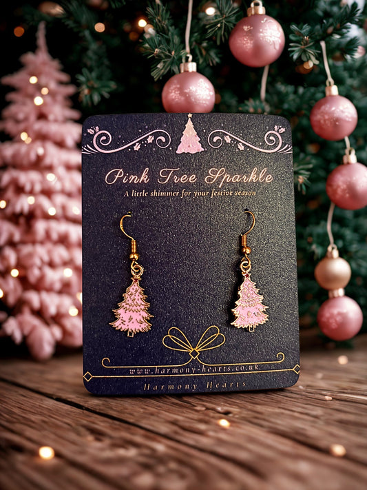 Pink tree-shaped earrings on a card with Christmas decorations in the background