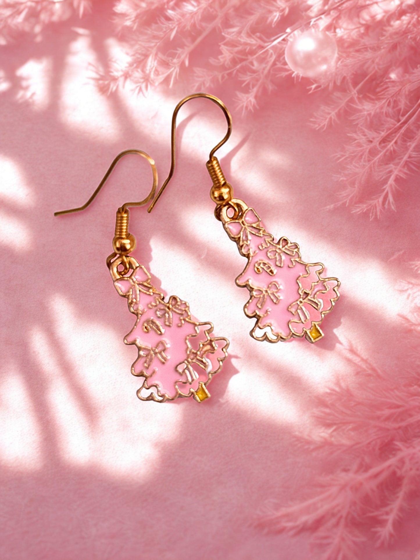 Pink and gold Christmas tree earrings  on a pink background with floral elements