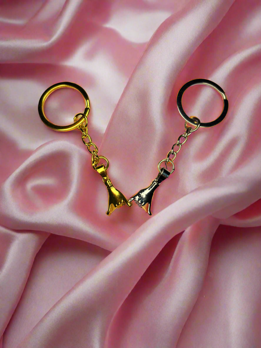 Gold and black keychains on a pink satin background