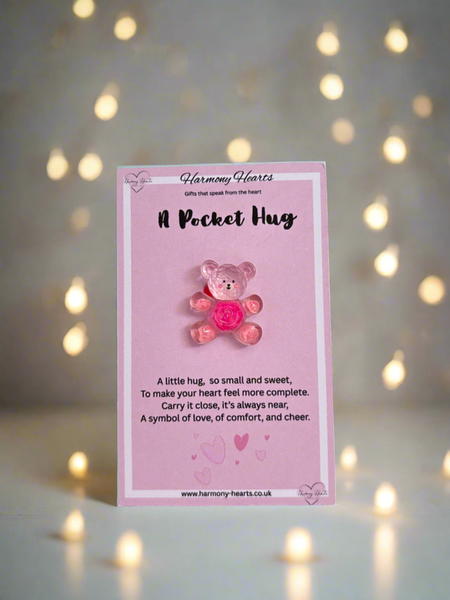 Pink card with a teddy bear charm and text on a blurred light background