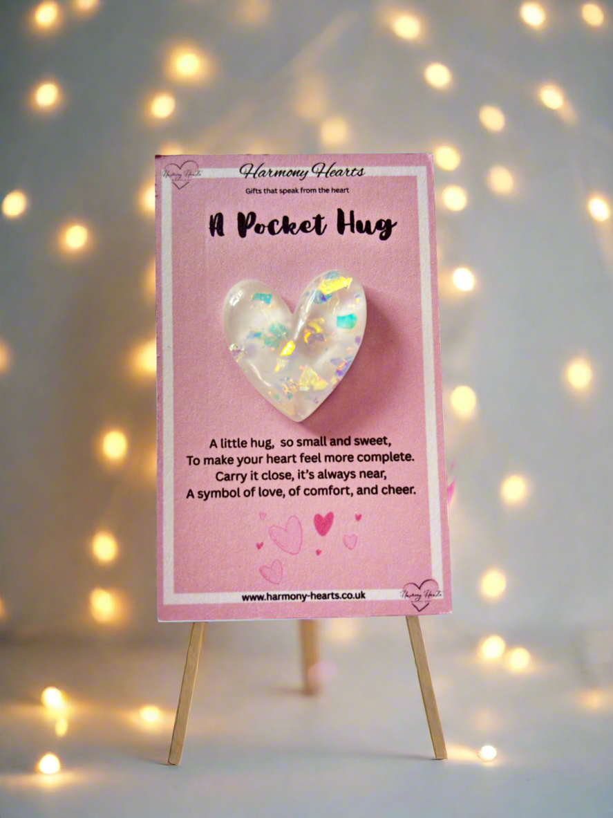 Heart-shaped product on a pink card with text, displayed on a stand against a softly blurred light background.