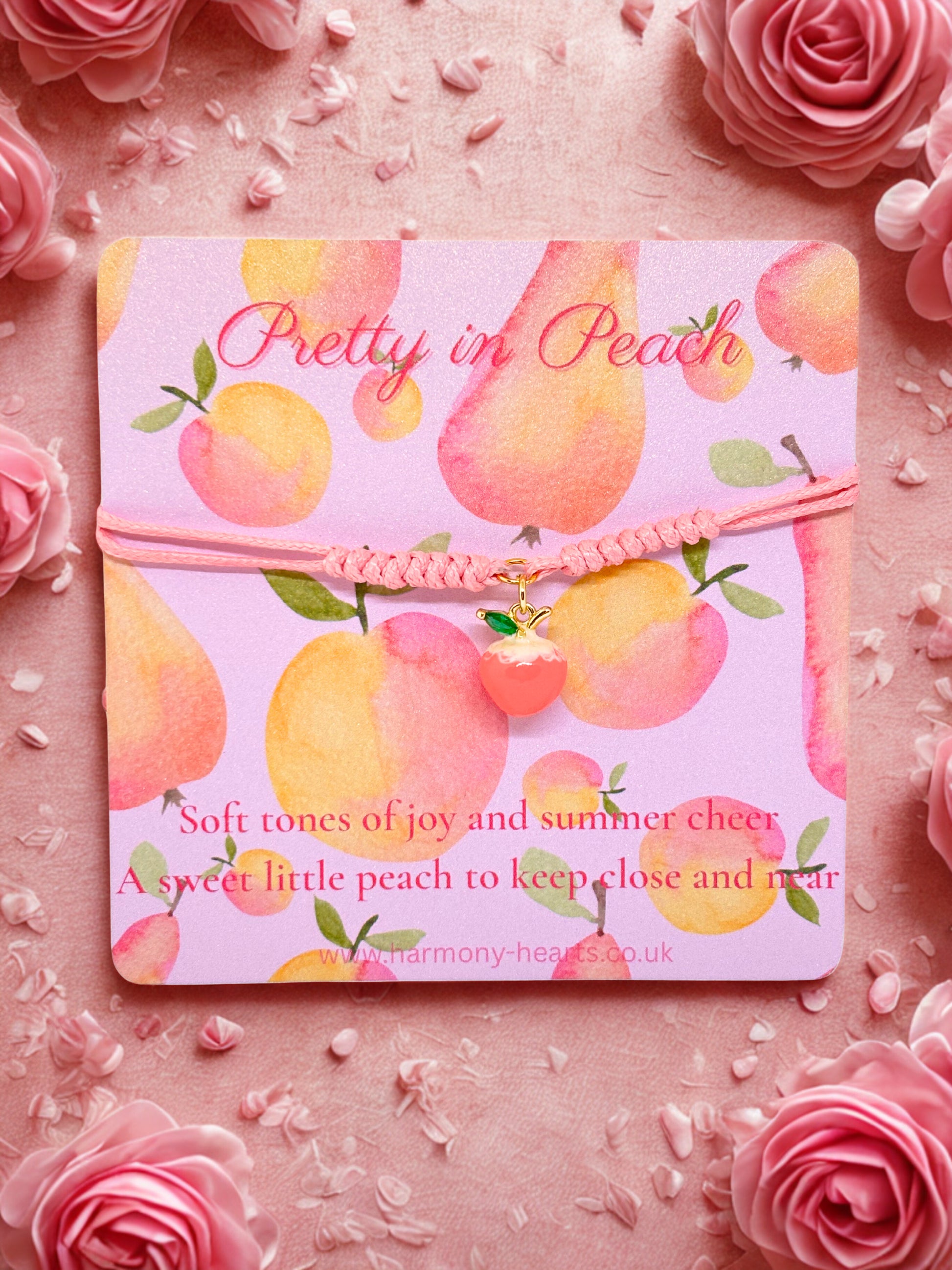 Peach charm bracelet on a branded card with peach design and text on a pink floral background