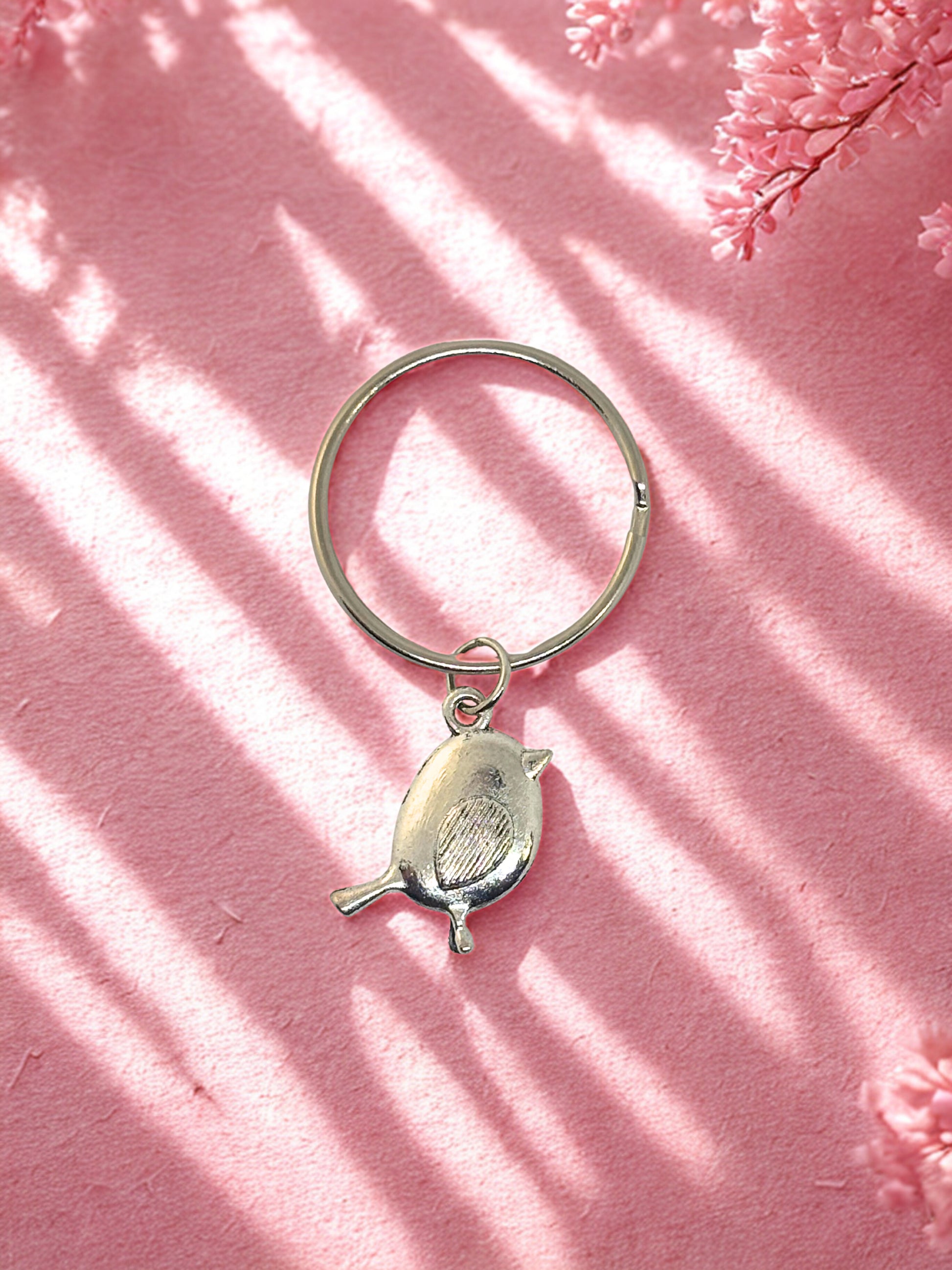 Silver keychain with a robin design on a pink background