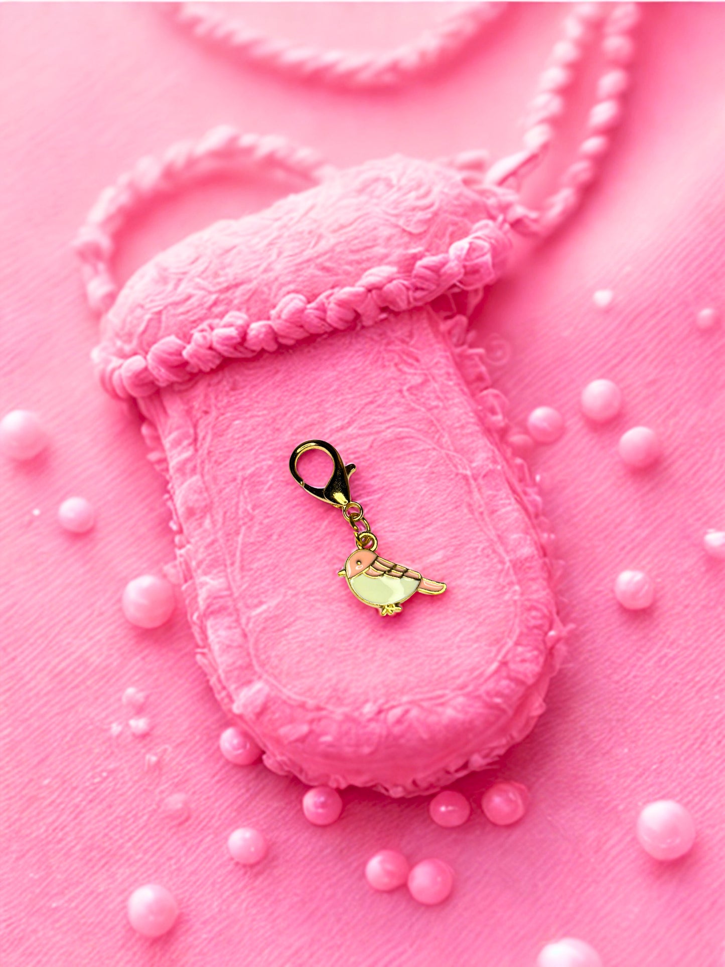 Pink robin with a gold charm on a pink background