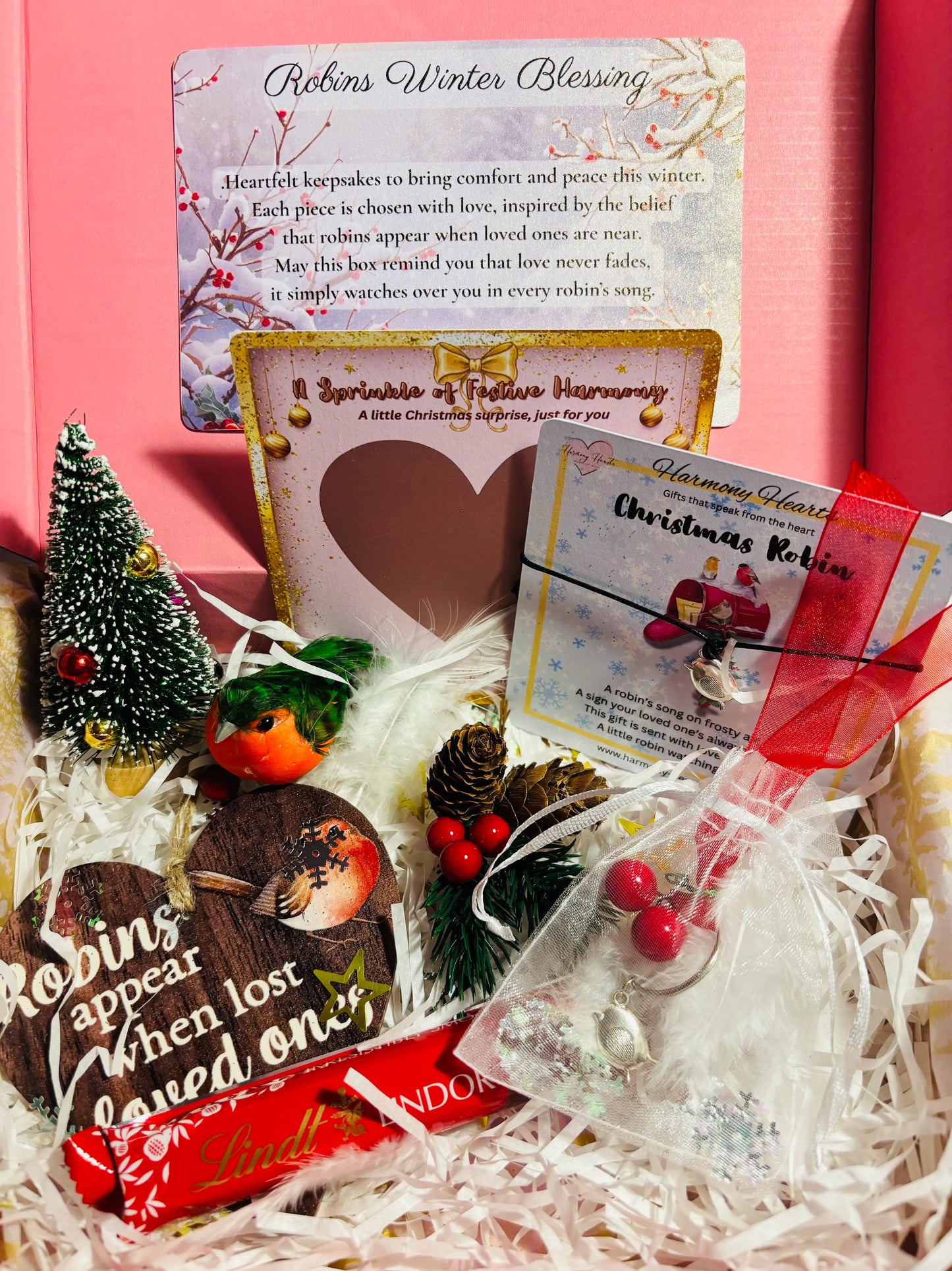 Decorative gift set with Christmas-themed items and cards on a pink background