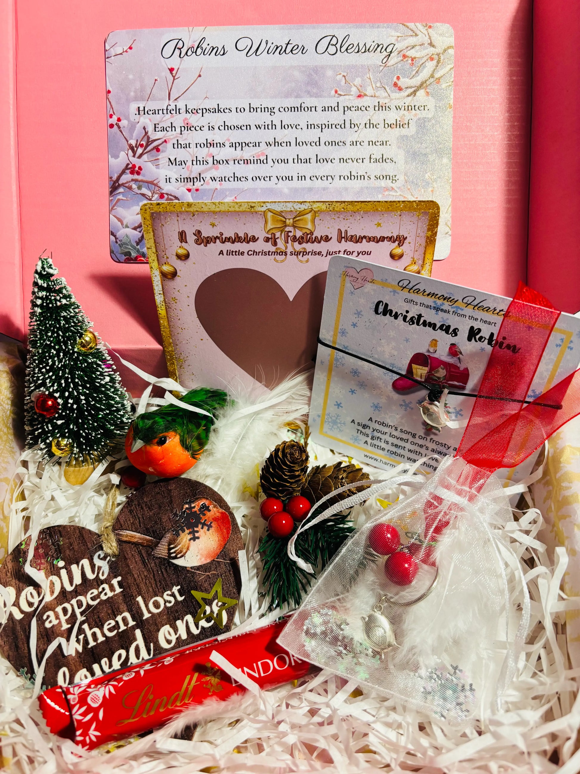 Decorative gift set with Christmas-themed items and cards on a pink background