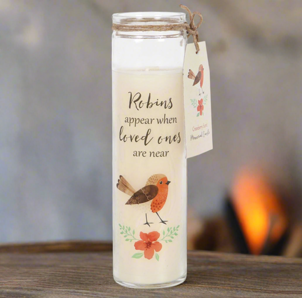Decorative candle with robin design and text on a wooden surface