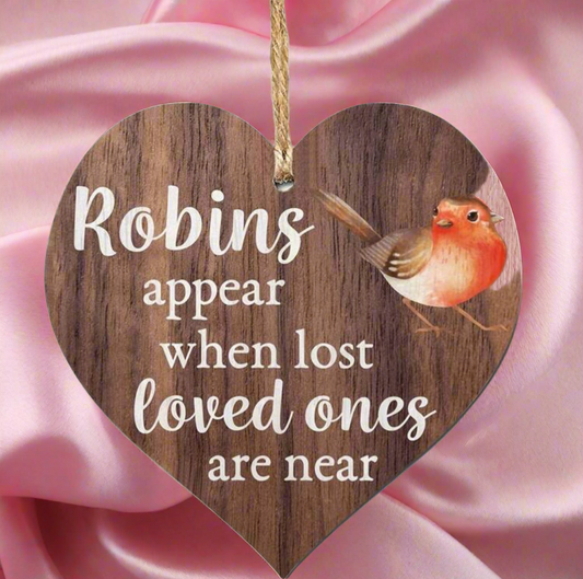 Wooden heart-shaped sign with a robin illustration and text on a pink fabric background