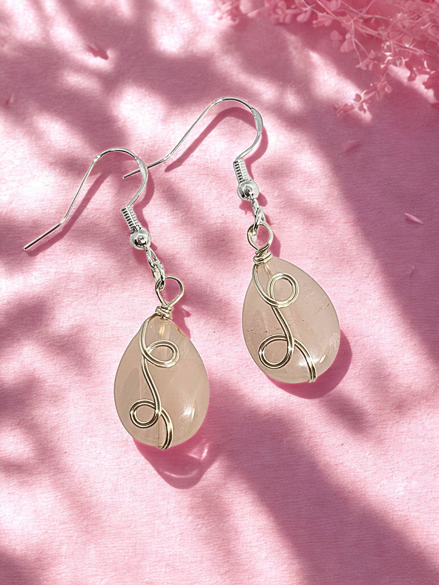 Pair of rose quartz earrings teardrop-shaped stones on a pink background