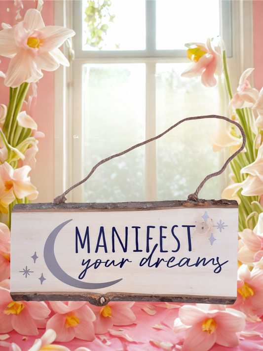 Decorative sign with 'Manifest your dreams' text surrounded by flowers.