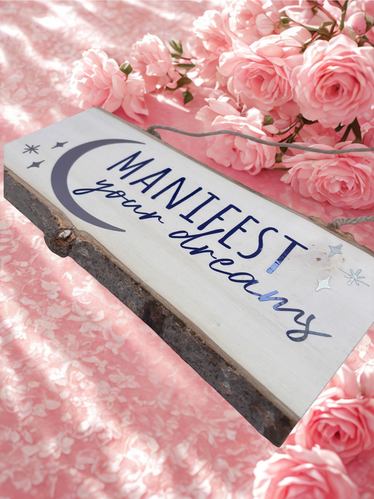 Decorative sign with 'Manifest your dreams' text on a pink floral background