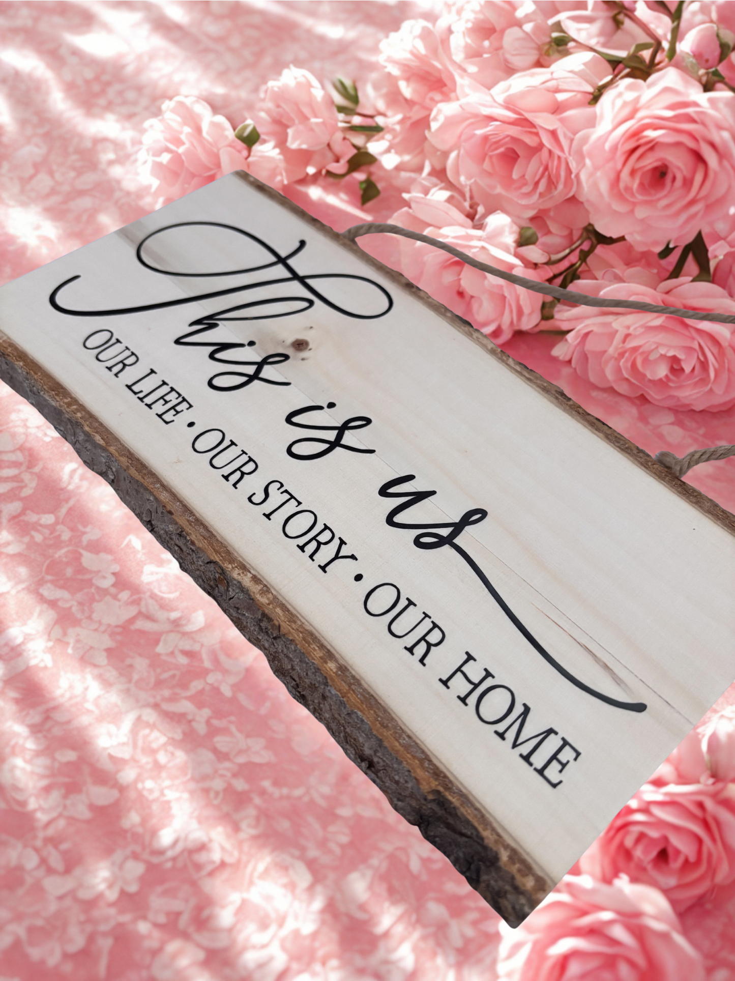Decorative sign with 'This is us, our life, our story, our home' text on a pink floral background