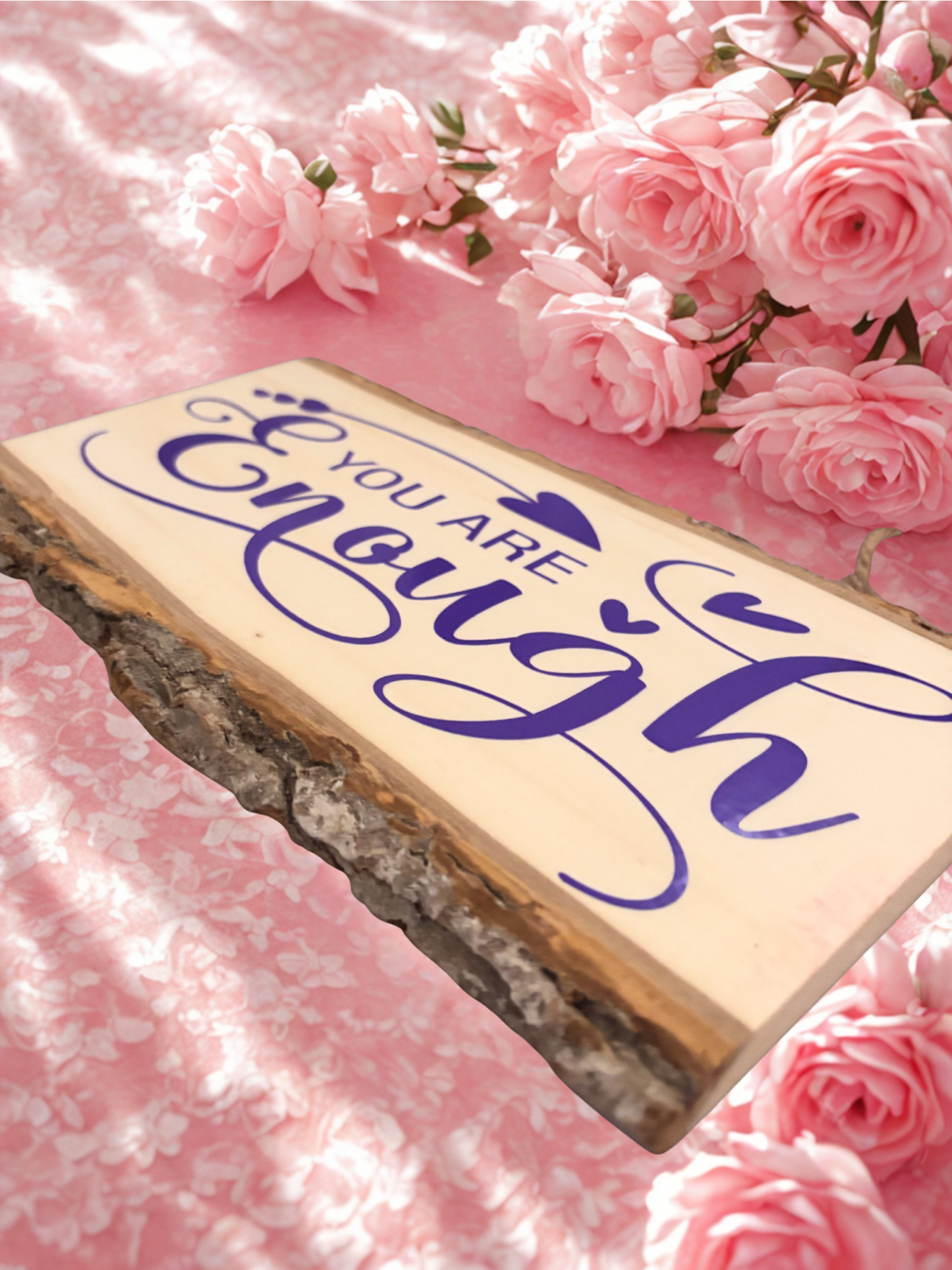 Wooden sign with 'You Are Enough' text on a pink floral background