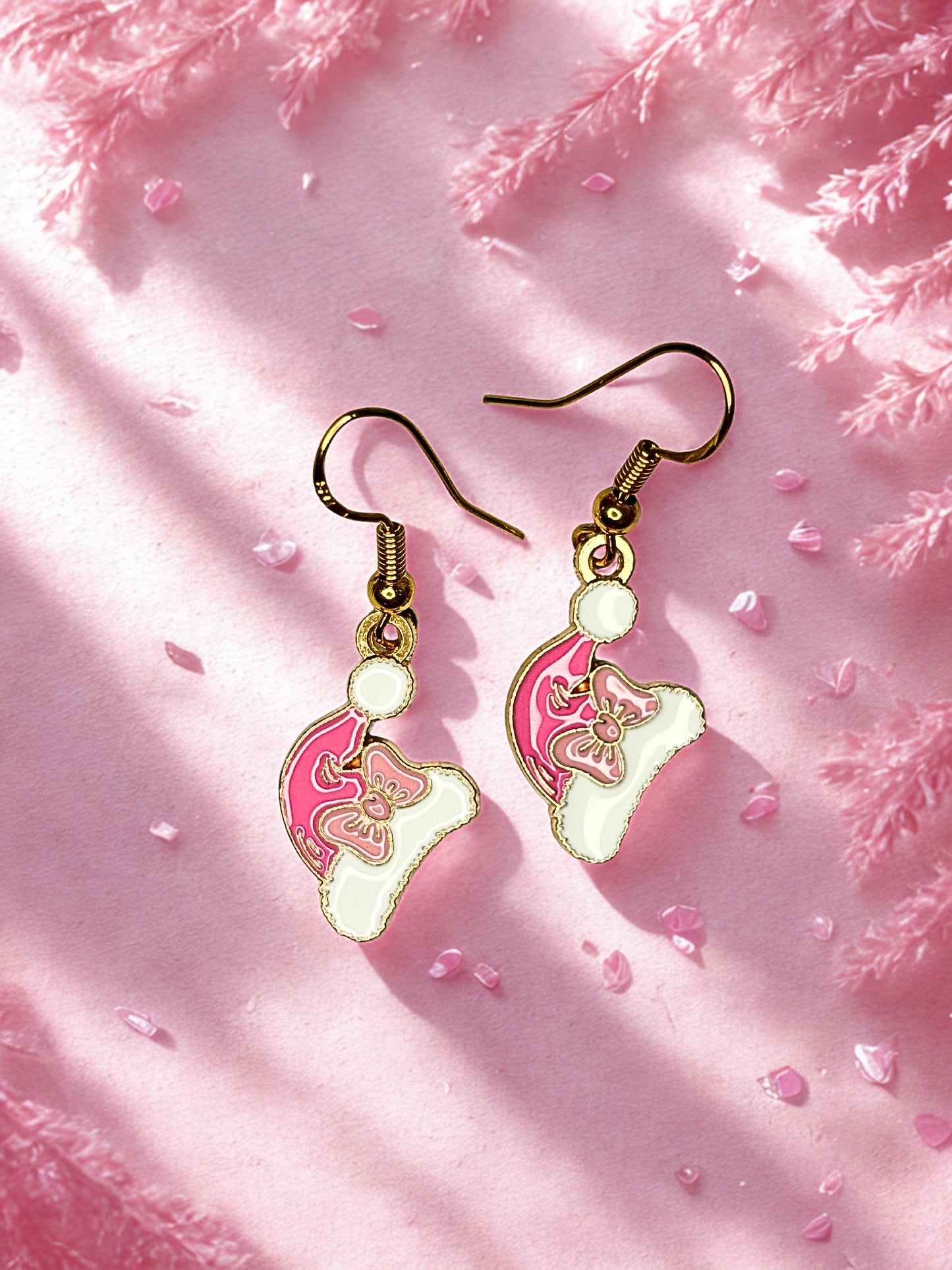 Pair of pink and gold santa hat earrings on a pink textured background
