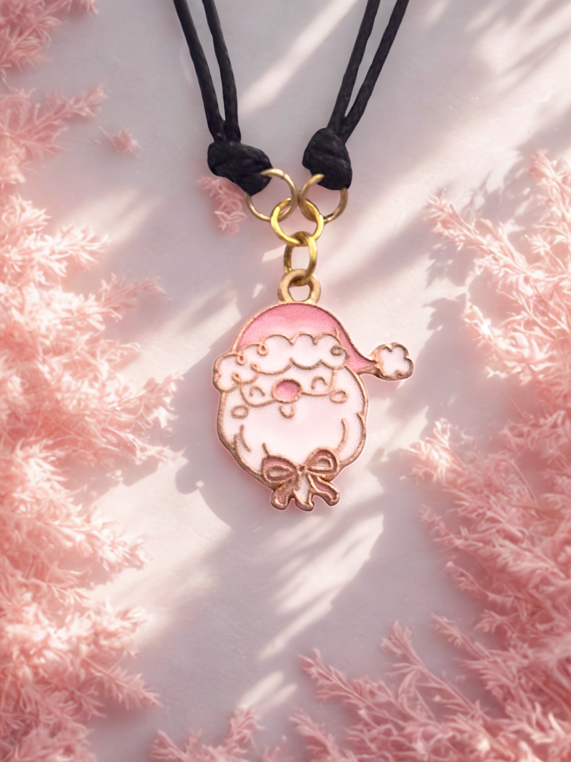 Pink Santa pendant on a black cord against a pink textured background