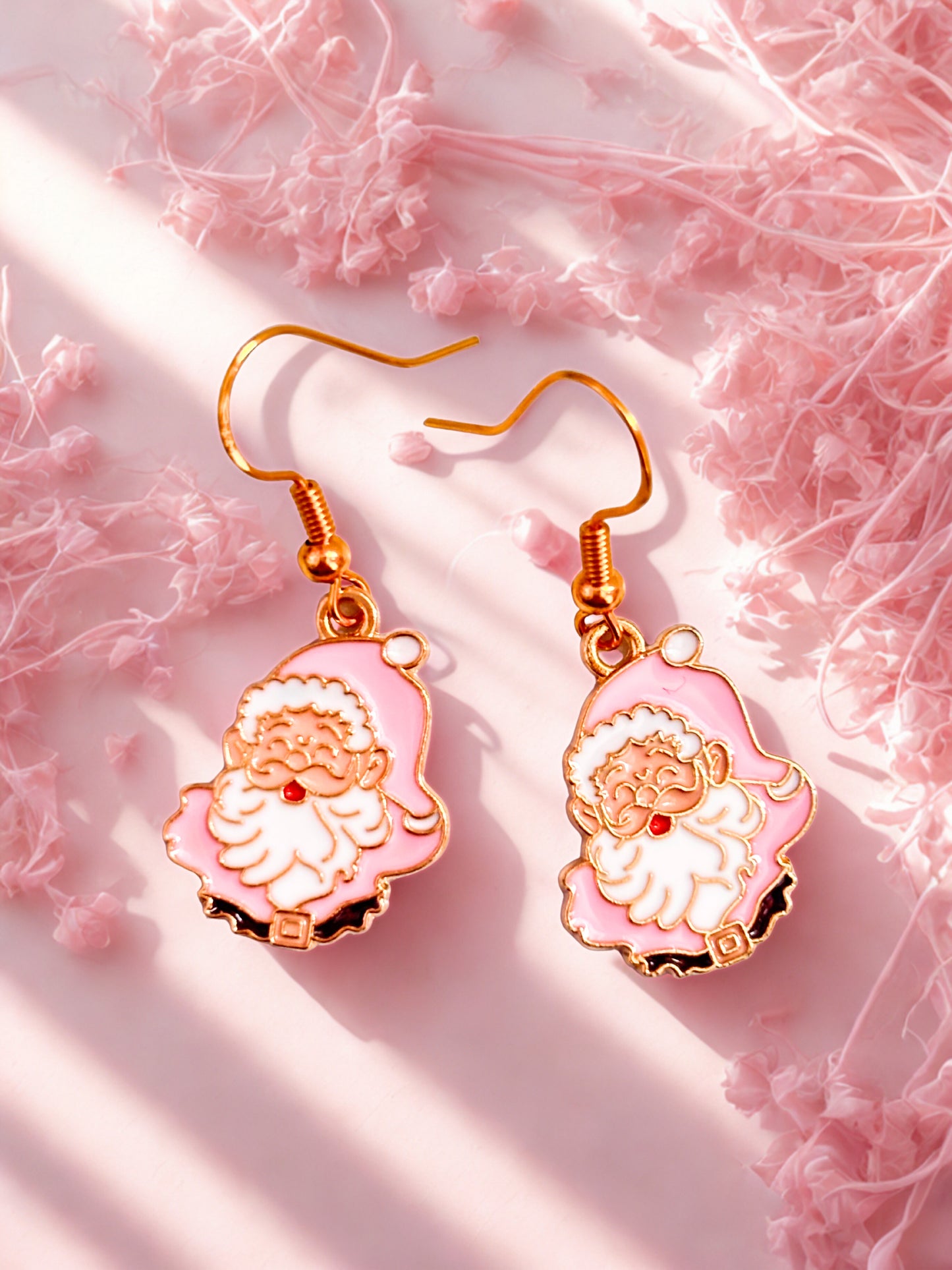 Pink and gold earrings with Santa Claus design on a pink textured background