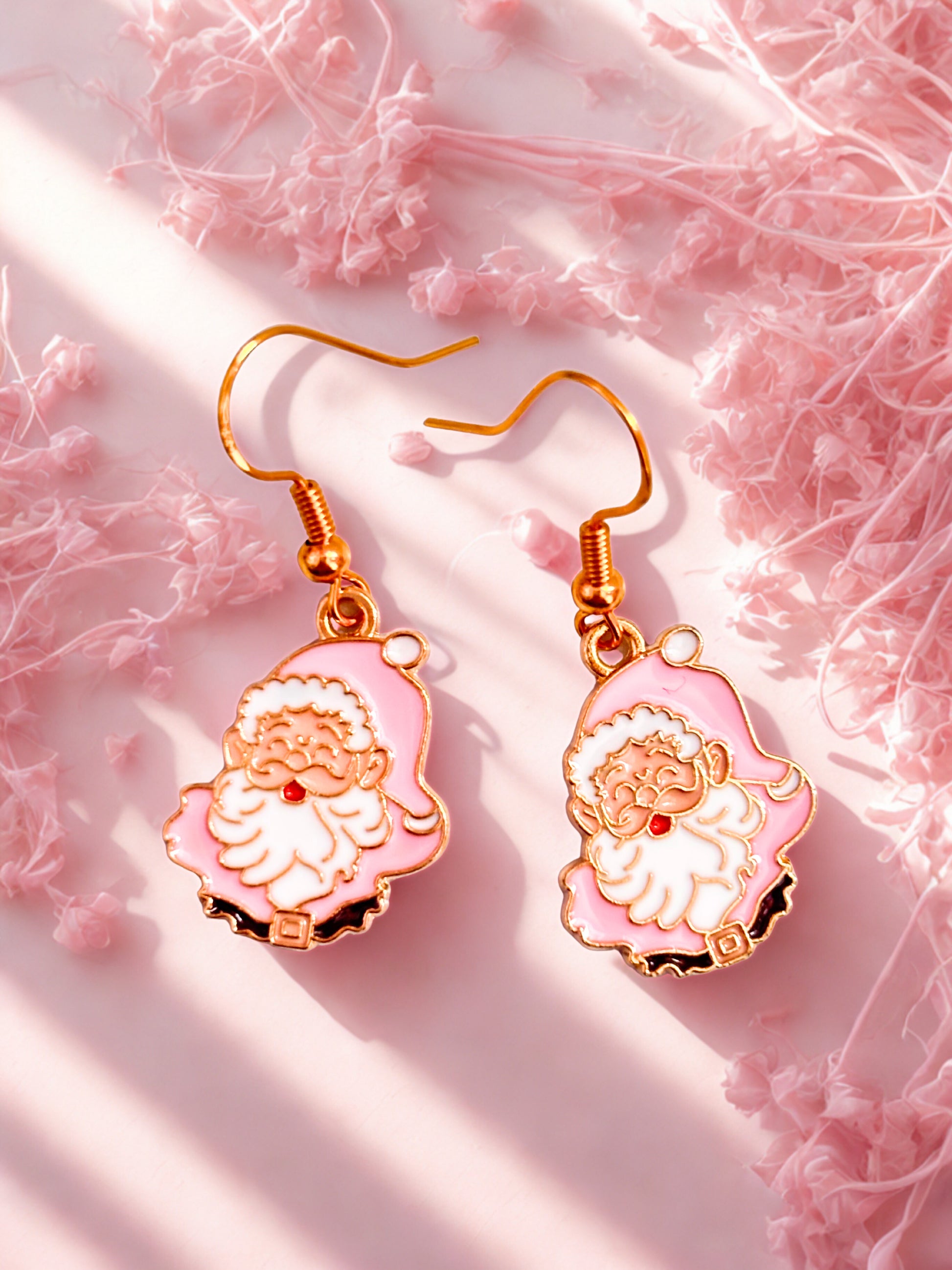 Pink and gold earrings with Santa Claus design on a pink textured background