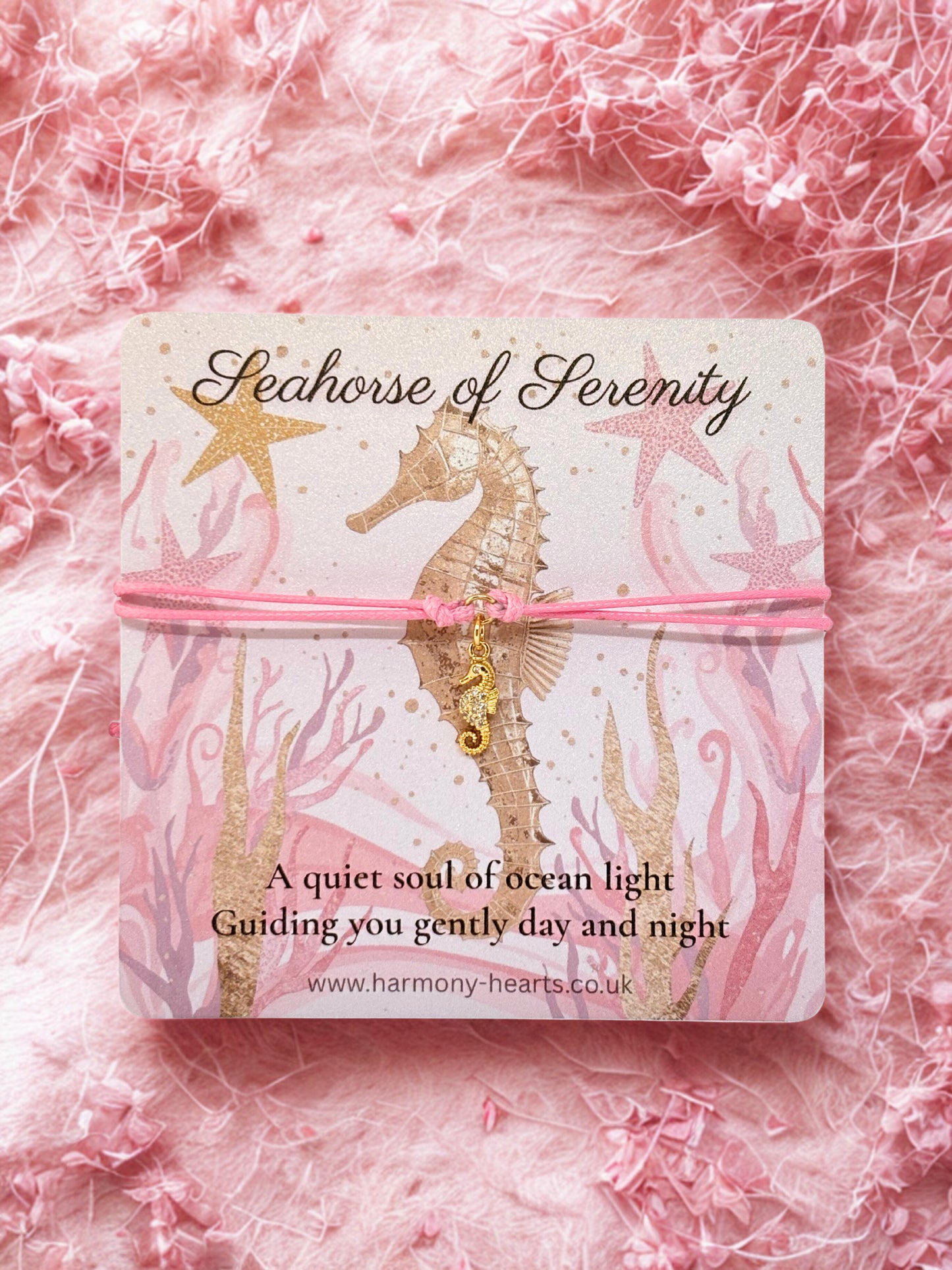 Seahorse charm on a pink background with 'Seahorse of Serenity' packaging.