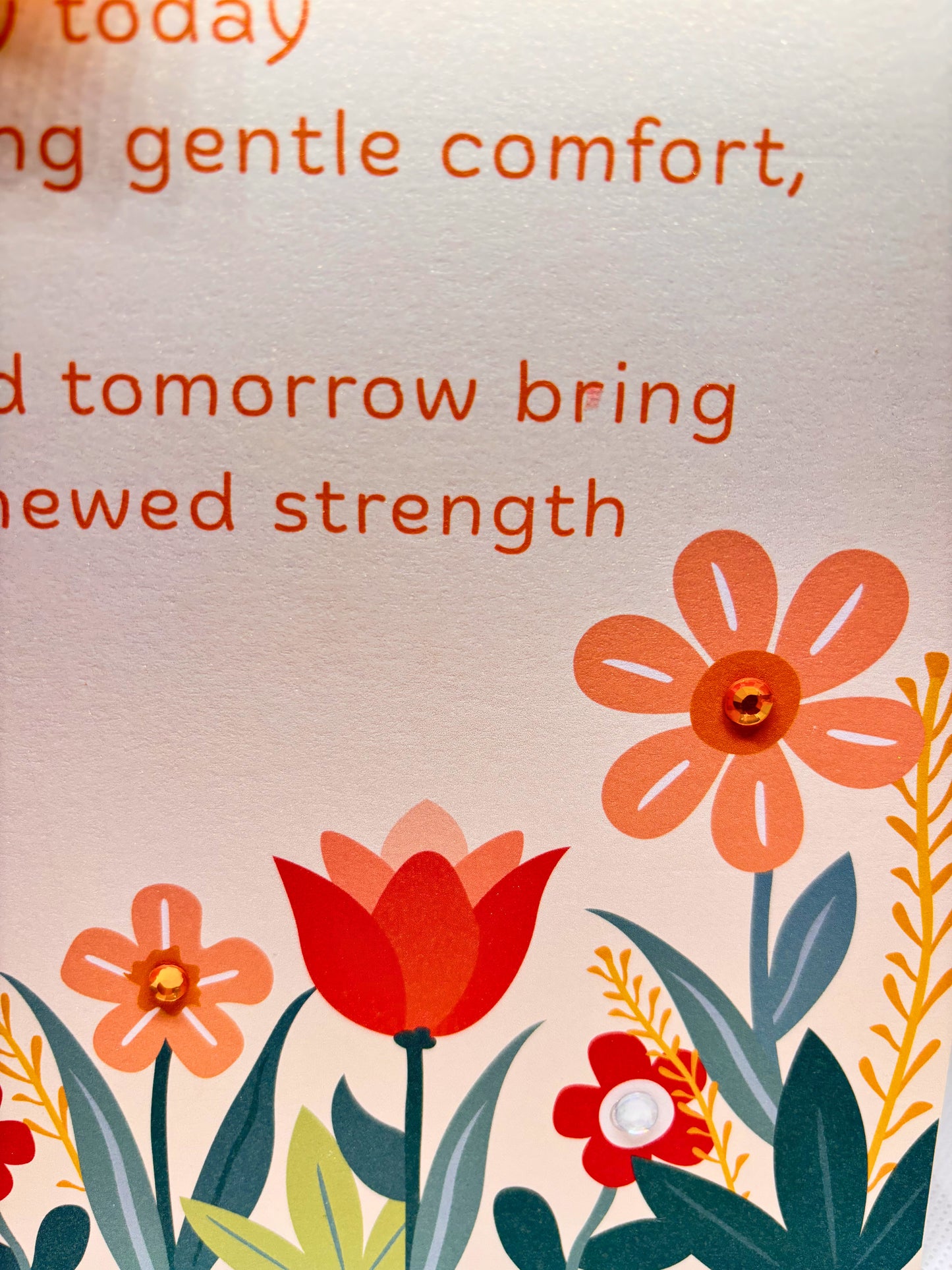 Close up of get well card with motivational text with floral illustrations on a beige background
