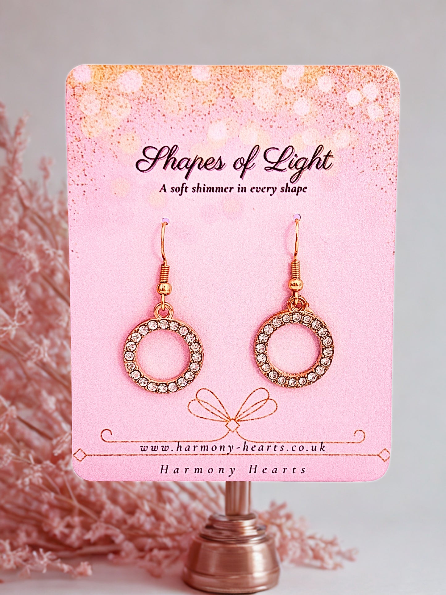 Pair of circular earrings on a 'Shapes of Light' branded card with a pink gradient background.
