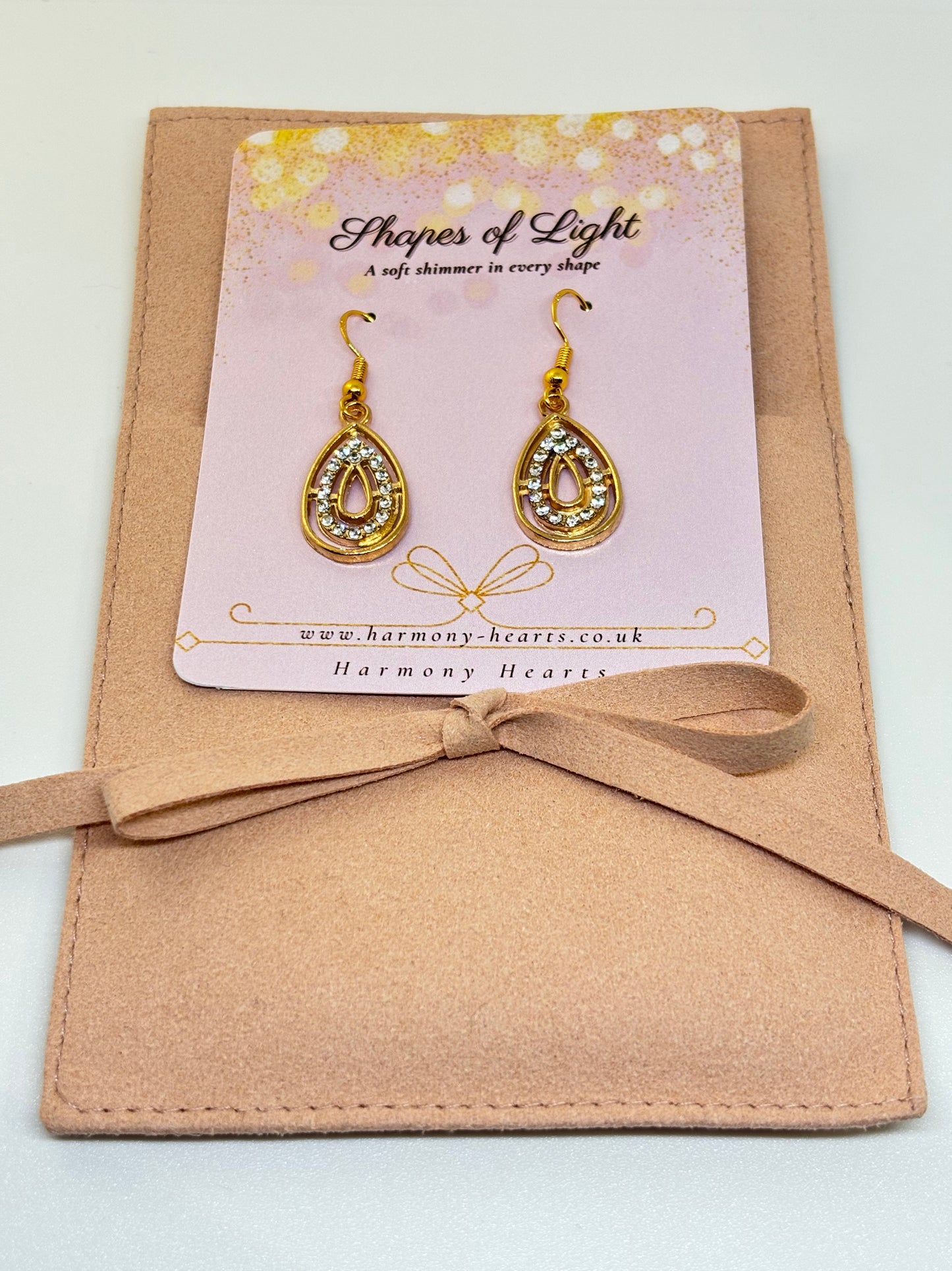 Gold earrings on a 'Shapes of Light' card with a beige envelope