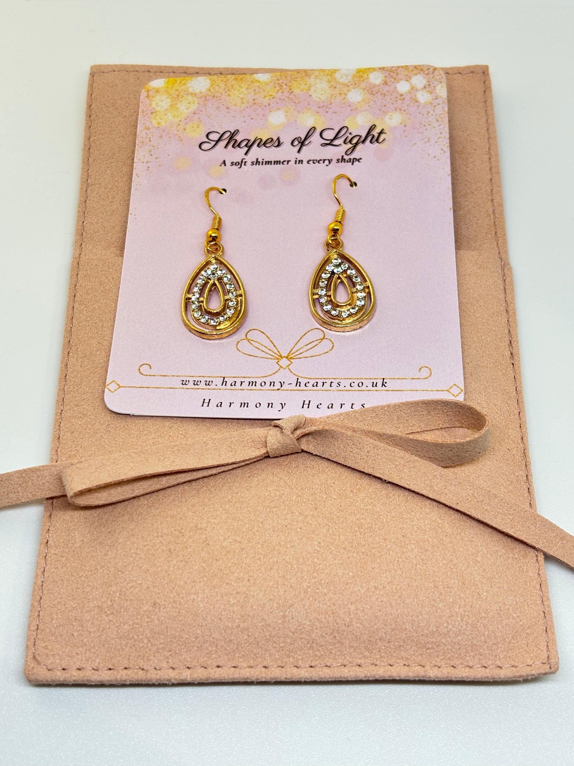 Gold earrings on a 'Shapes of Light' card with a beige envelope