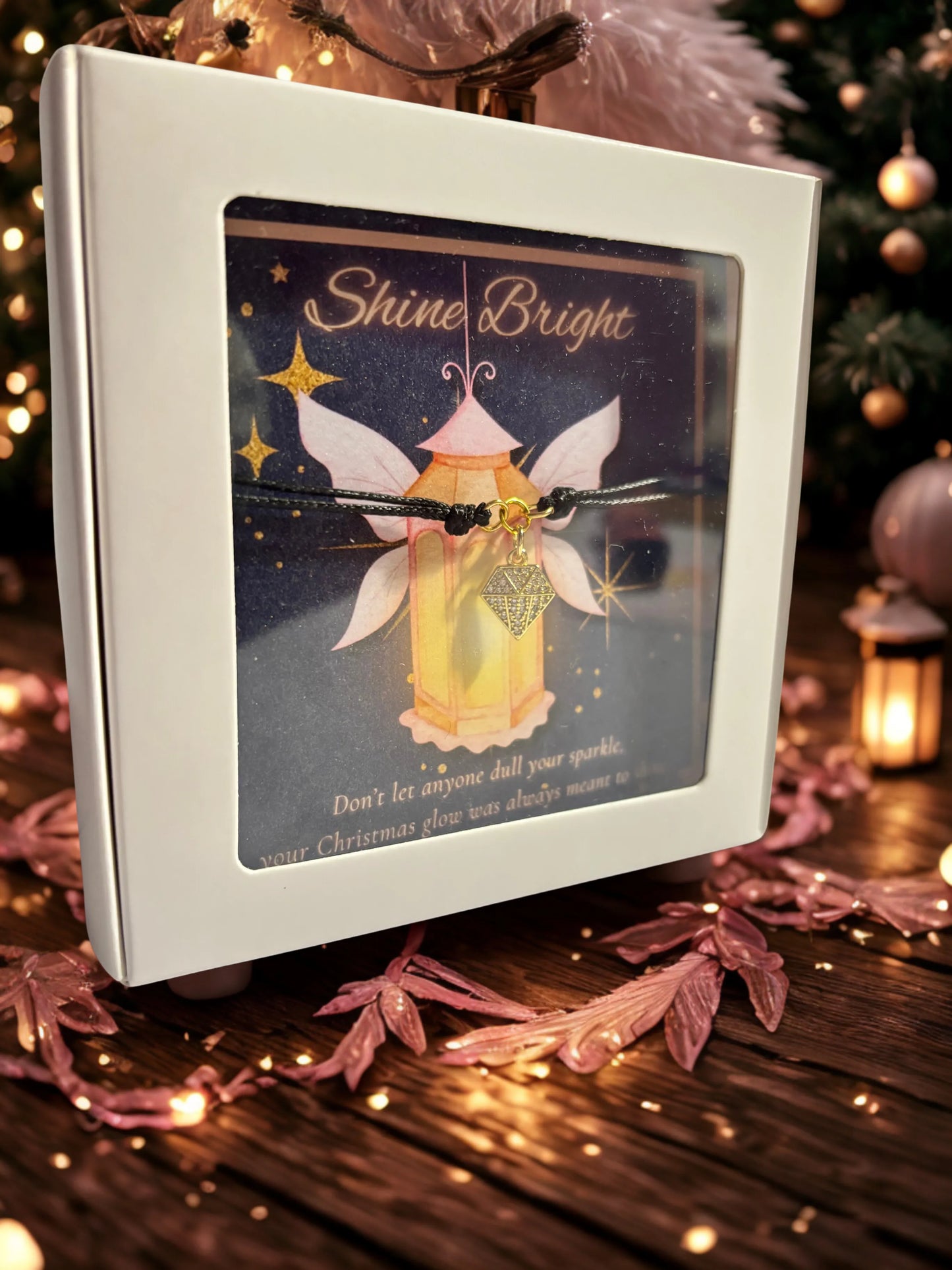Decorative card with fairy design and 'Shine Bright' text and a gold charm bracelet, surrounded by festive decorations.