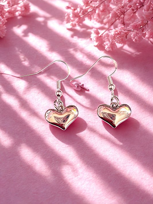 Heart-shaped earrings on a pink background with floral elements