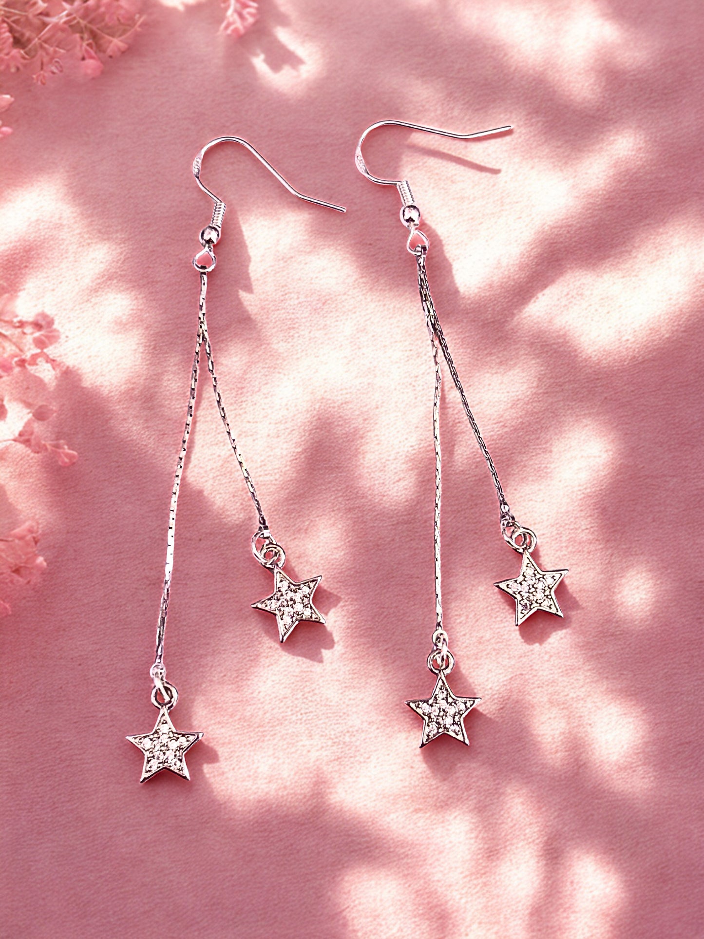 Star-shaped earrings on a pink floral background
