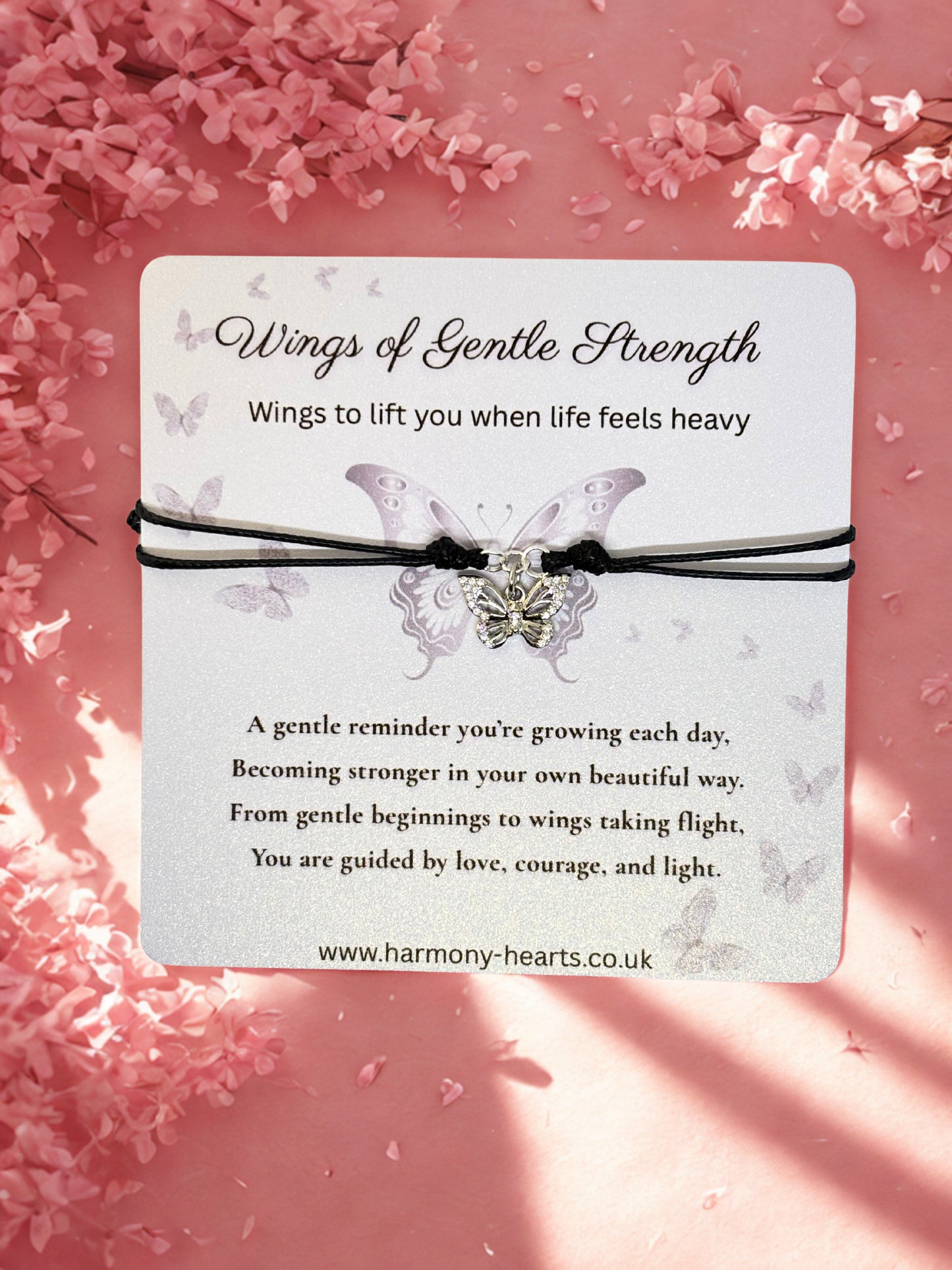 Butterfly bracelet with 'Wings of Gentle Strength' message on a pink floral background