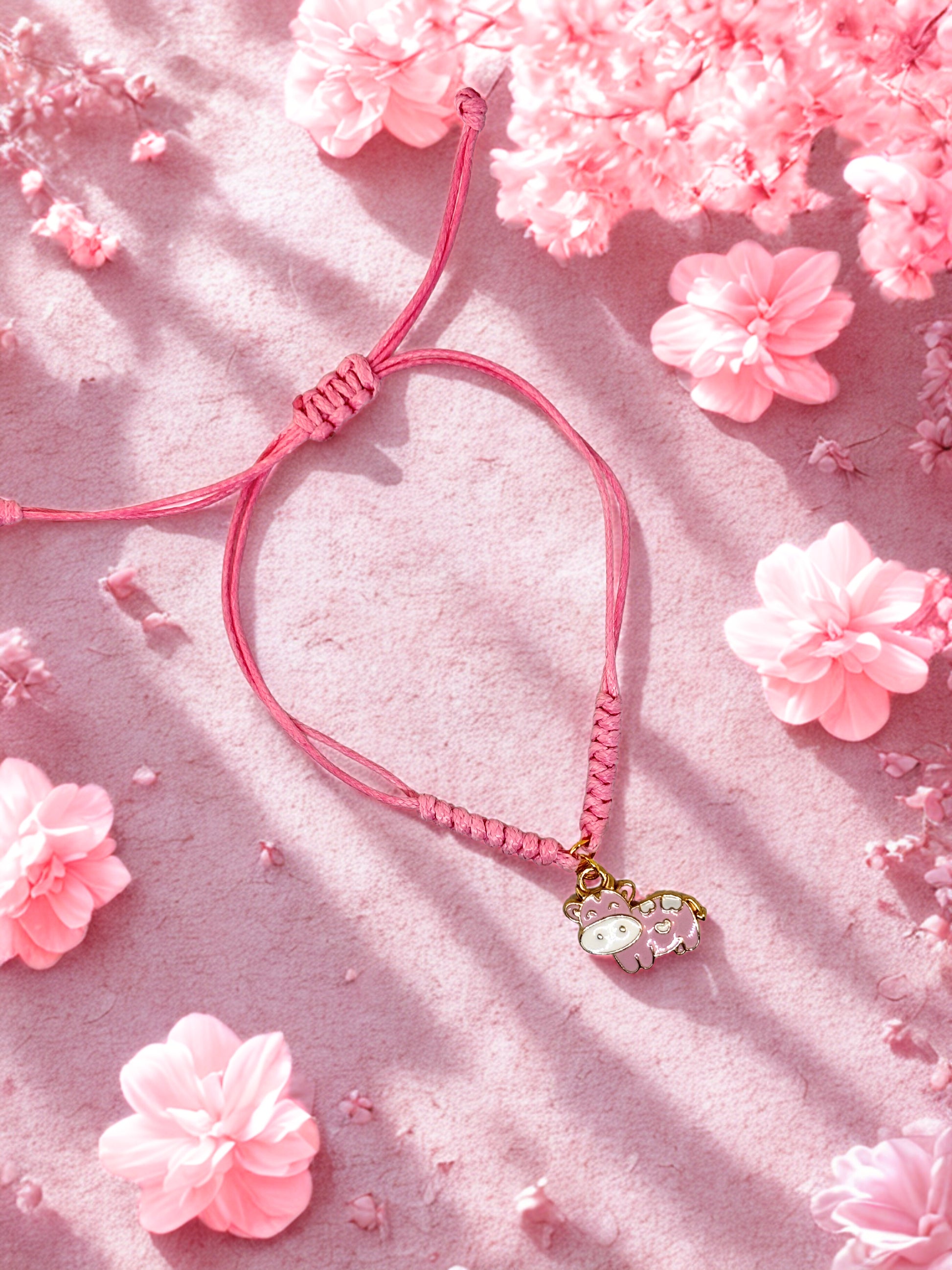 Pink cord bracelet with a pink cow charm on a pink background