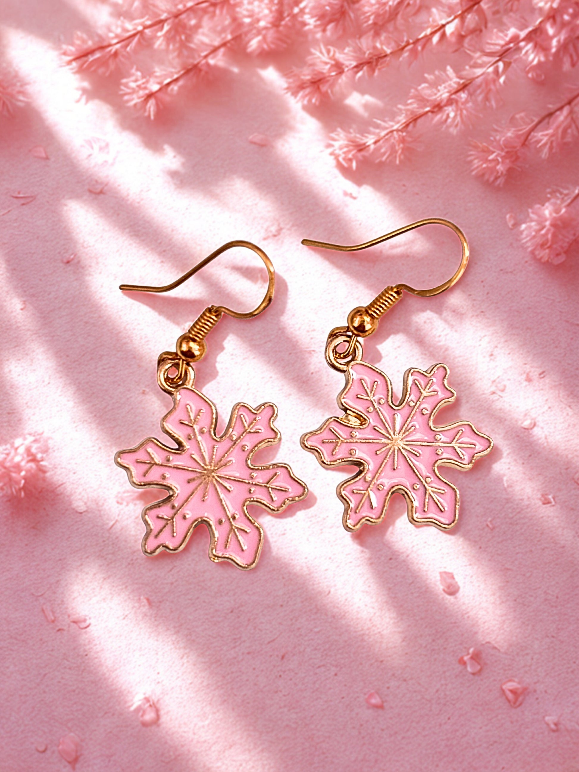 Pink snowflake earrings on a pink background with floral elements