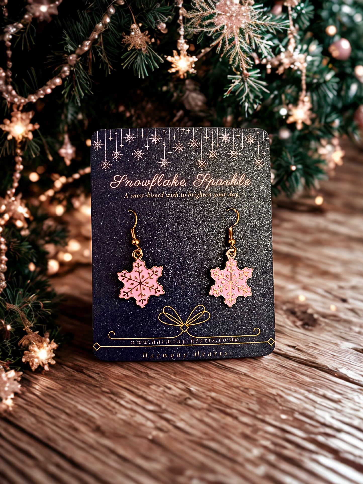 Snowflake earrings on a card with a Christmas tree in the background